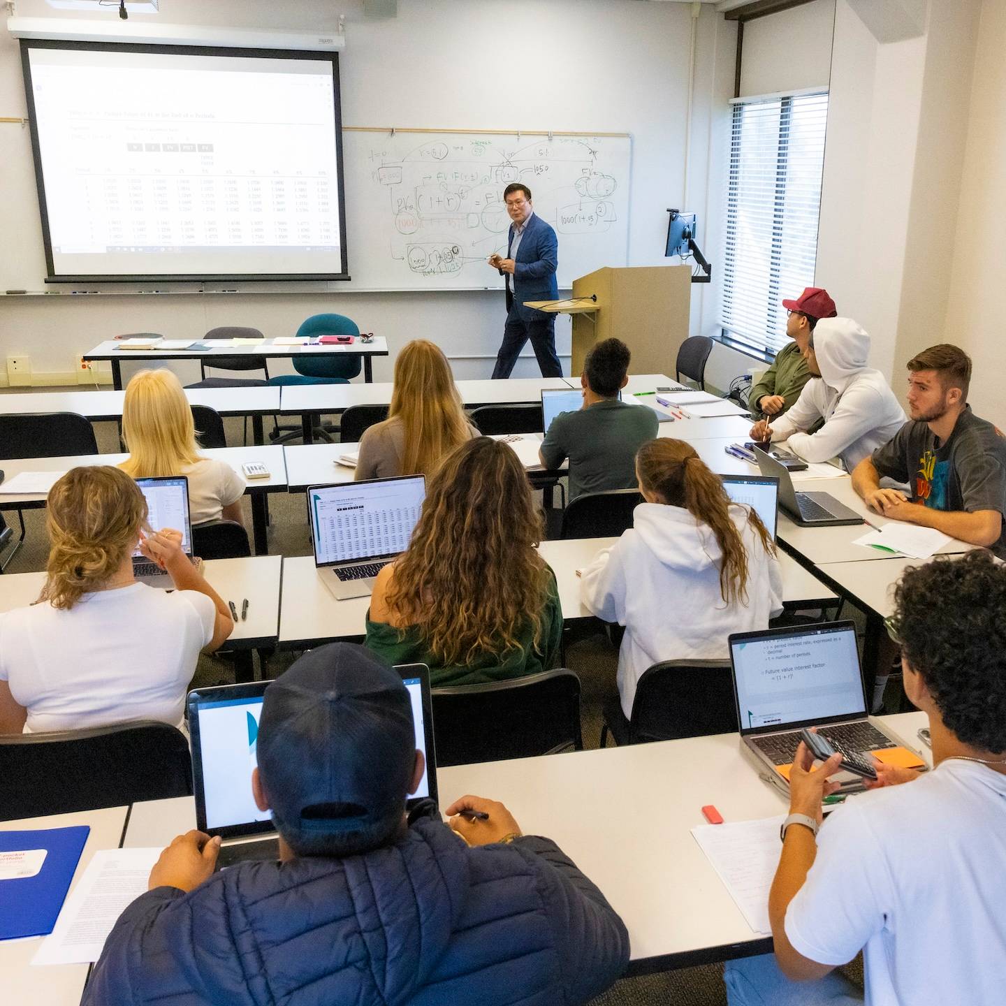 a person standing in front of a classroom with a group of people