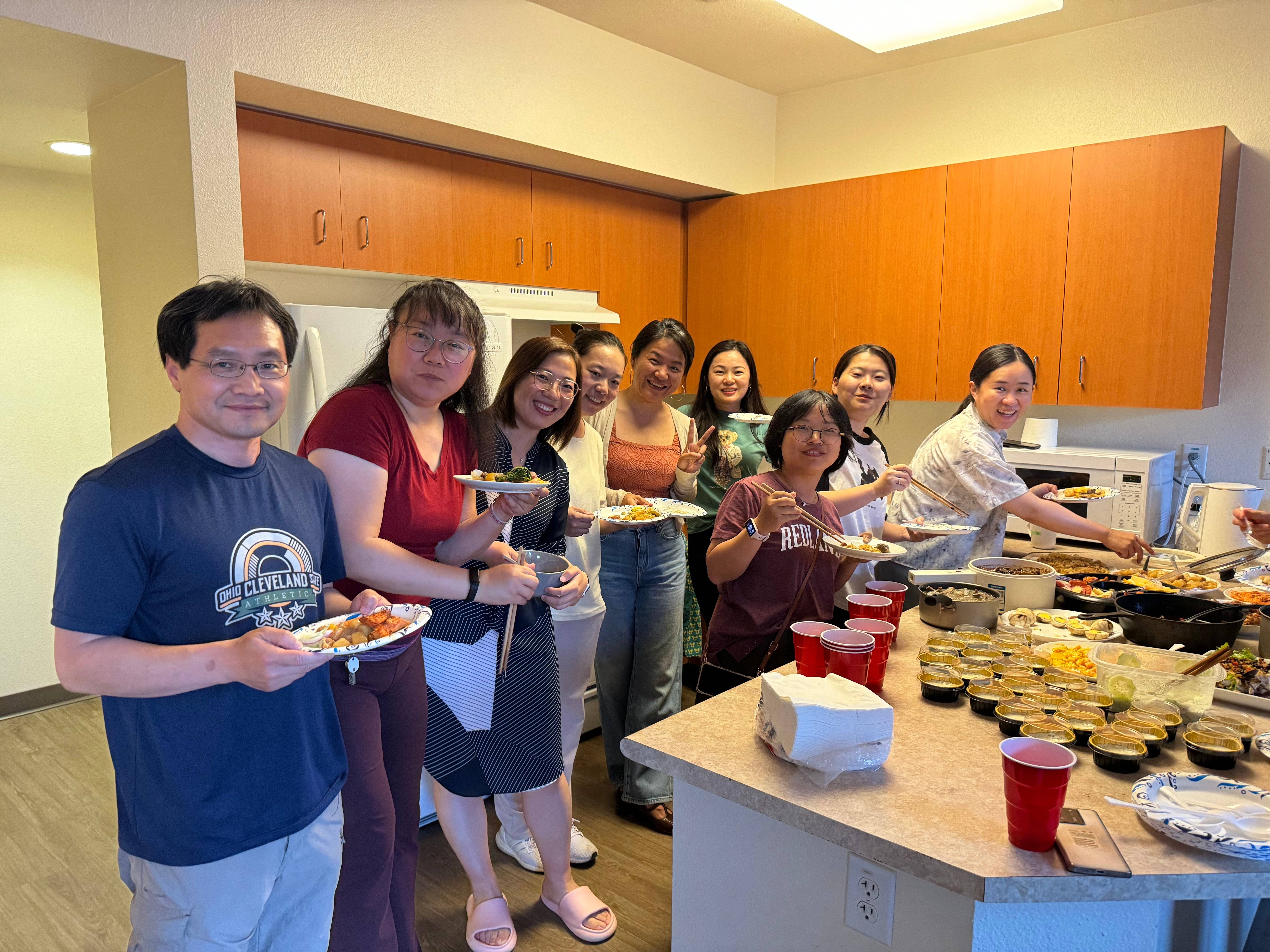 a group of people standing in a kitchen with food