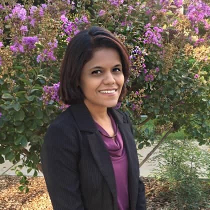 a person smiling in front of purple flowers