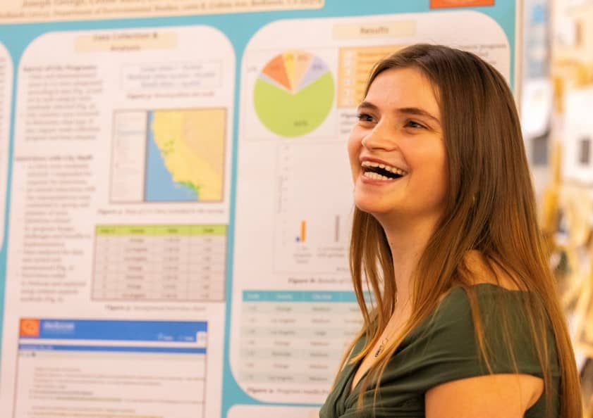a person smiling in front of a poster