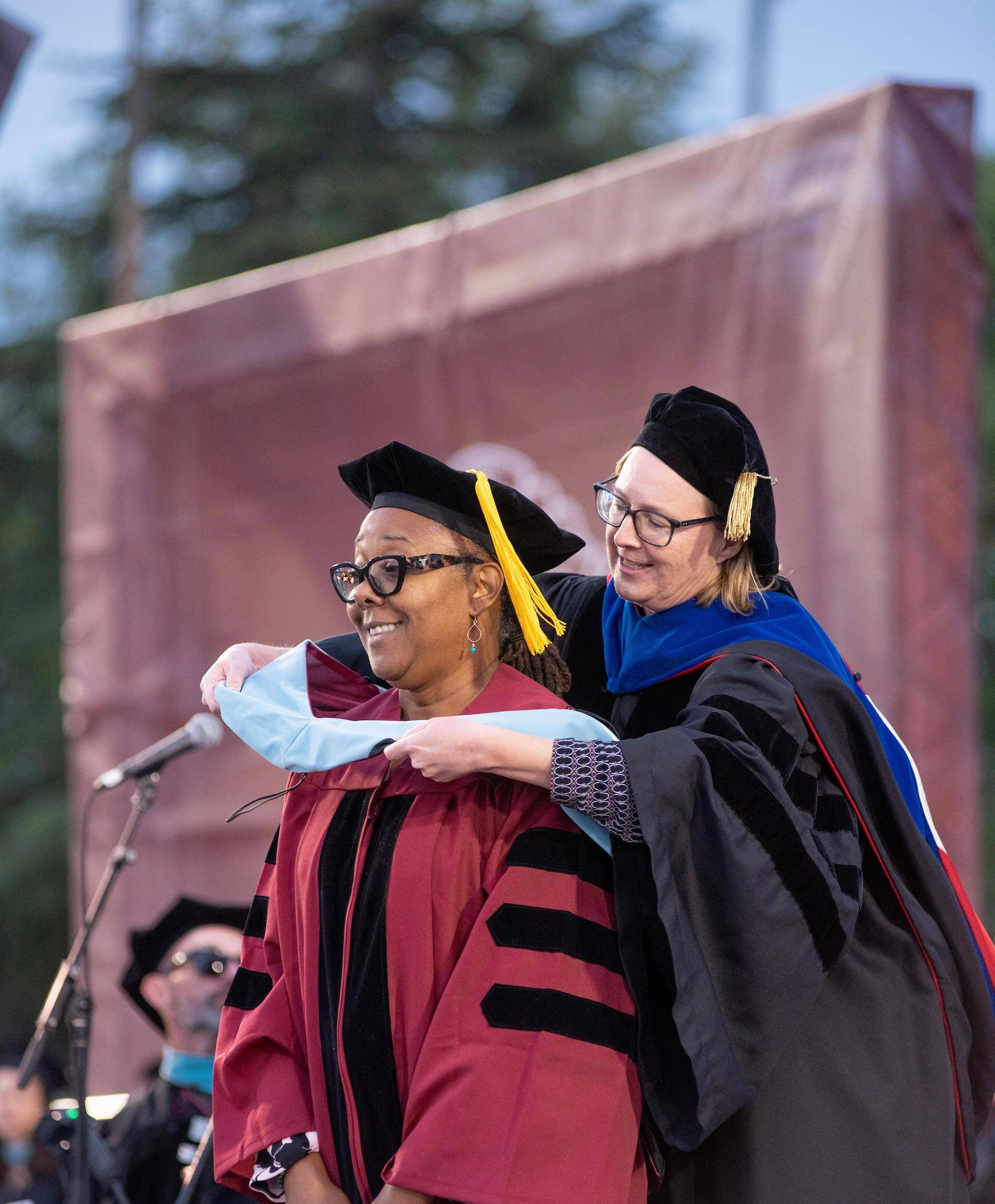 a person hugging a person in graduation gown