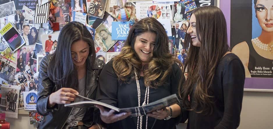 a group of women smiling and looking at a magazine