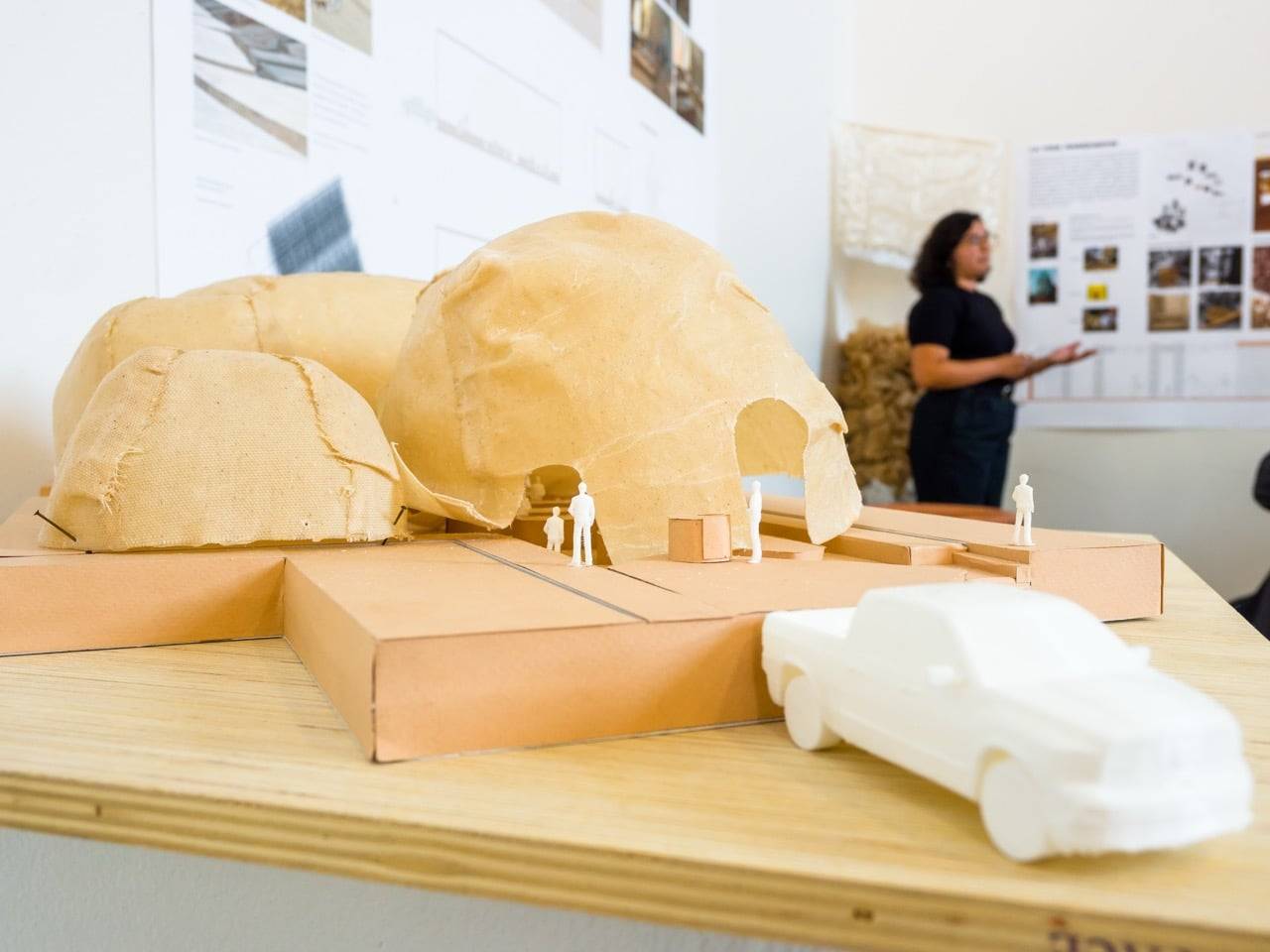 a model of a building with a car and a person standing in the background