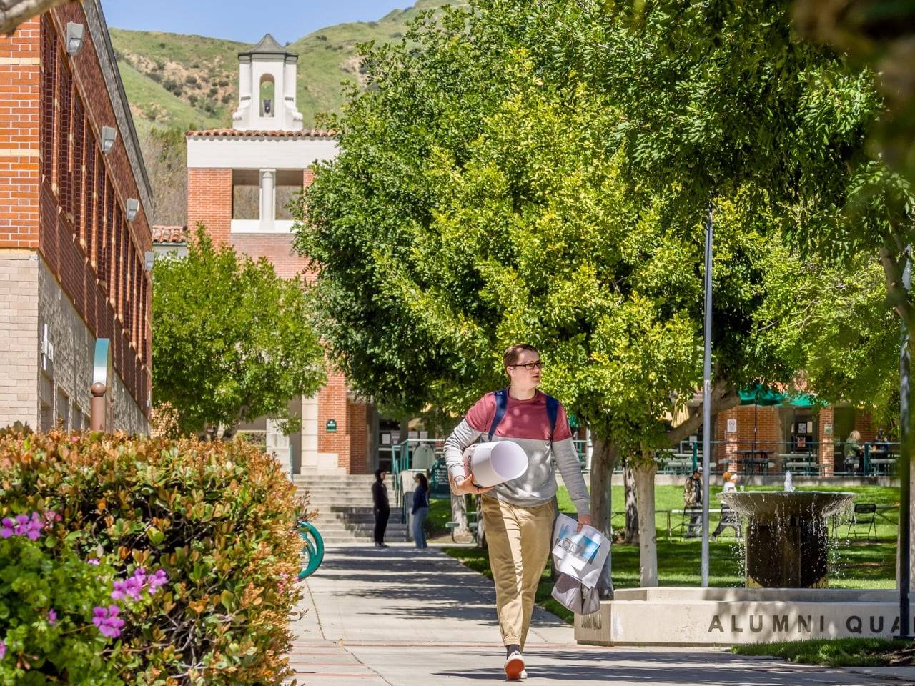 a person walking down a sidewalk with a building and trees