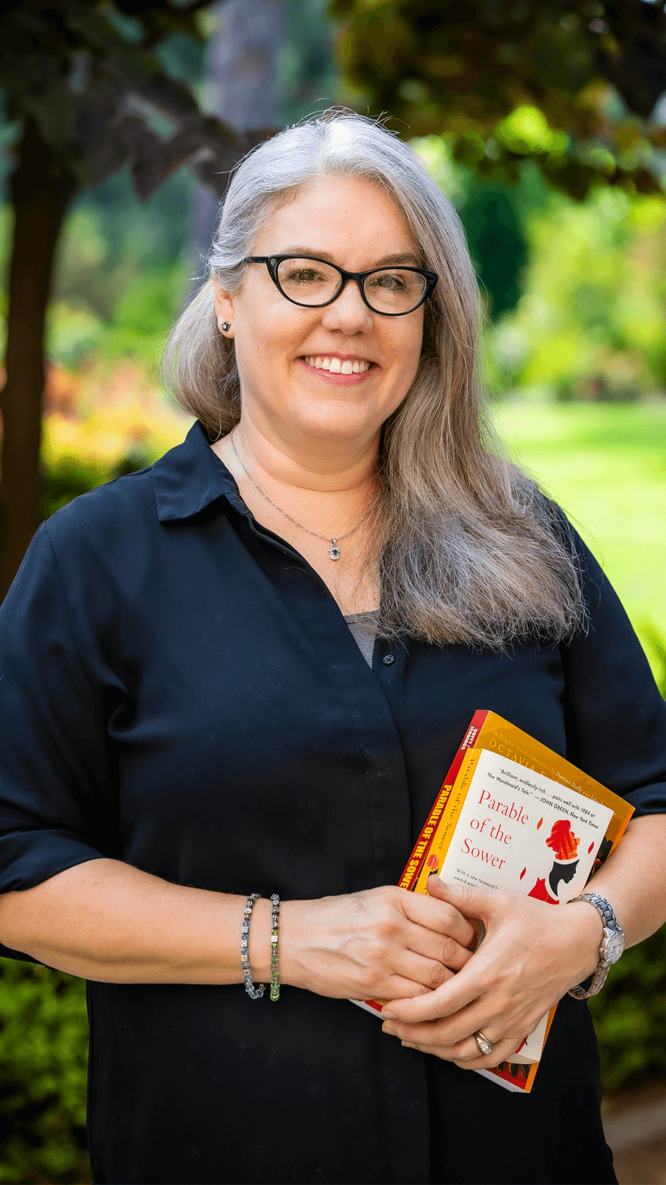 a person smiling with glasses and a book