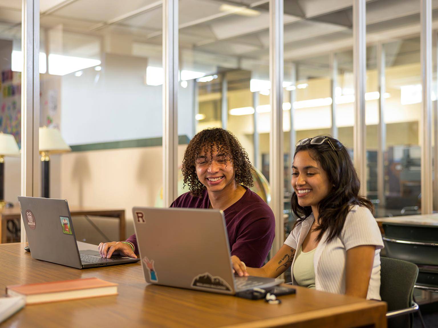 a couple of women sitting at a table with laptops