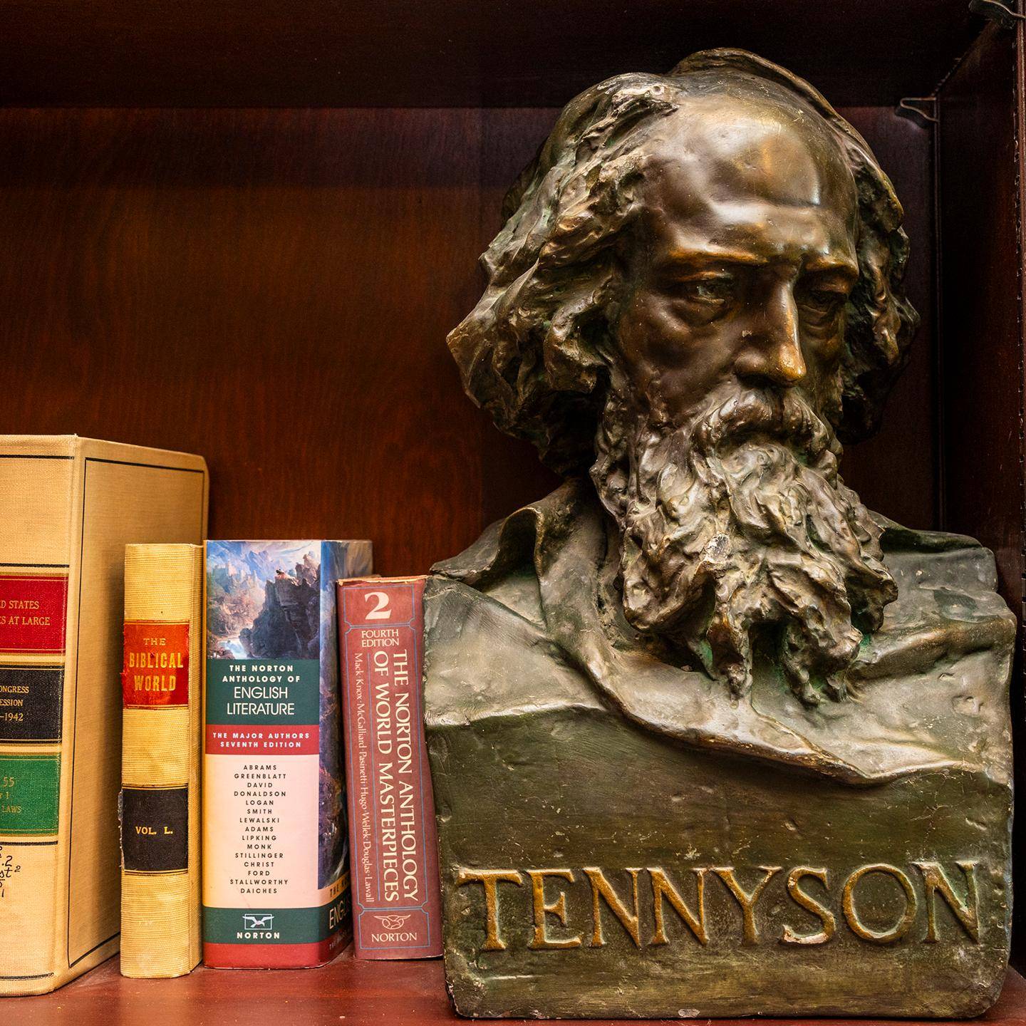a bust of a person with a beard and a book on a shelf