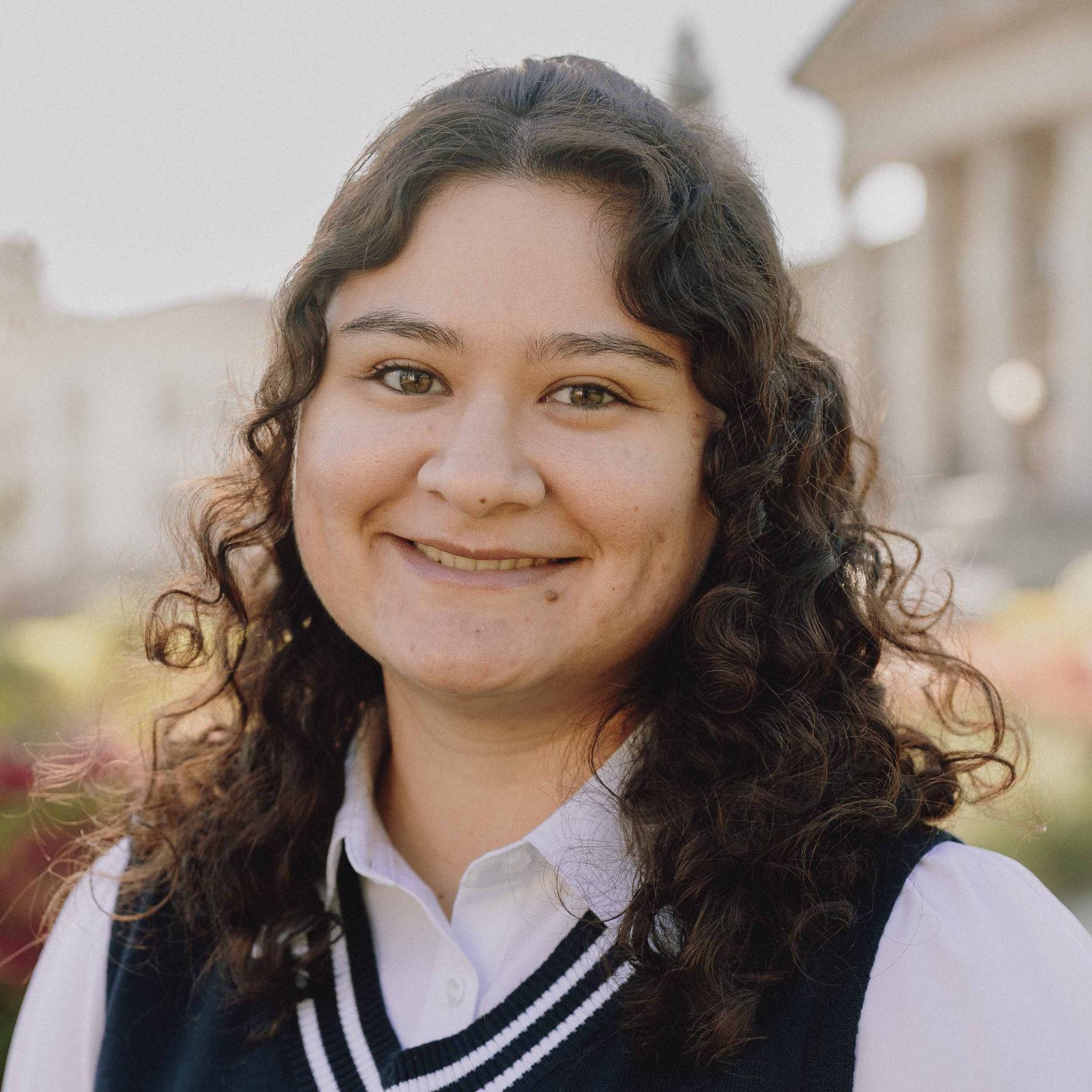 a person with curly hair wearing a vest
