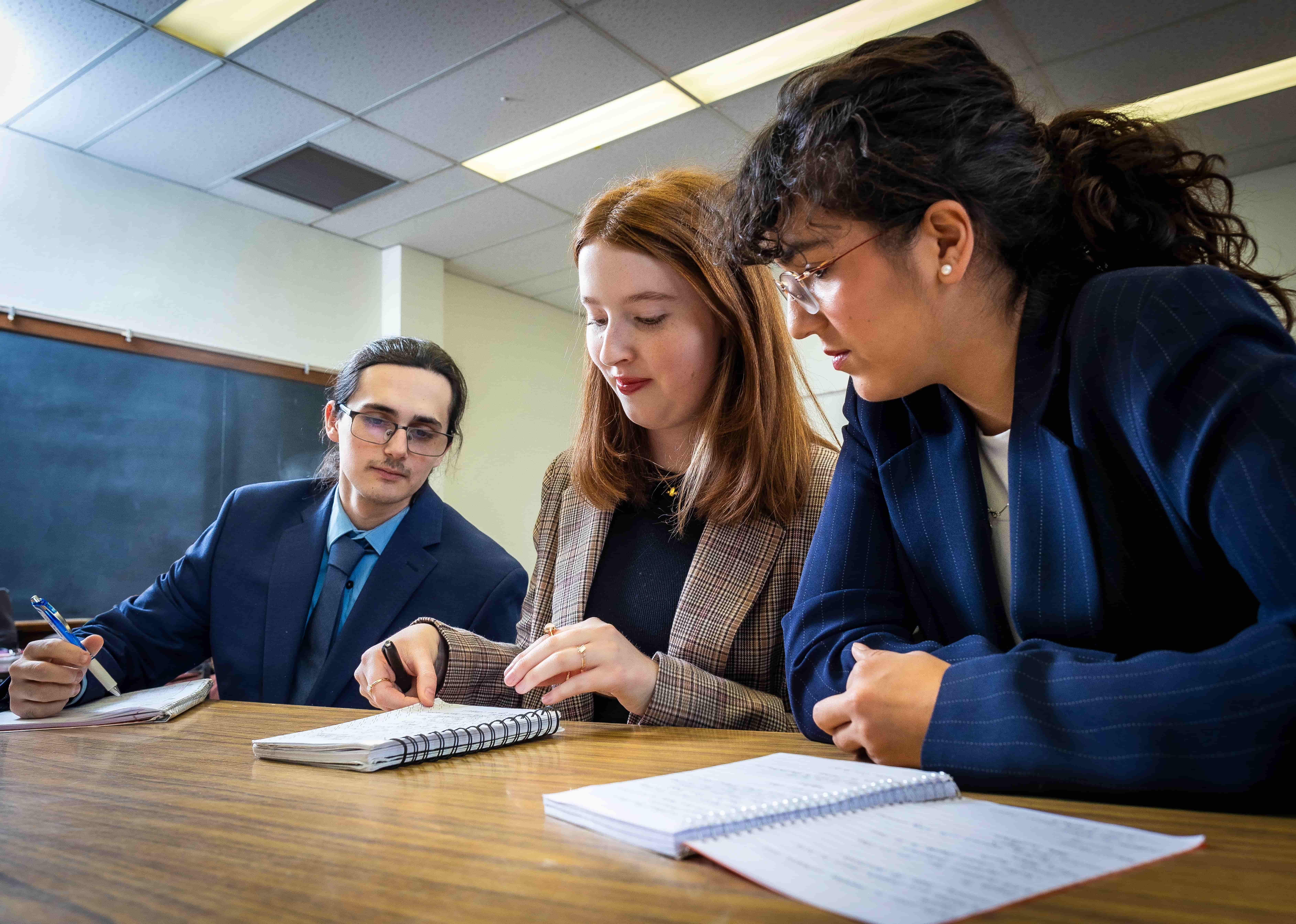 A group of students sitting at a table looking at a book
