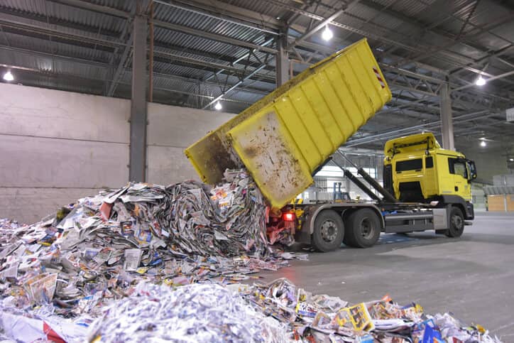a dump truck dumping paper into a pile of paper