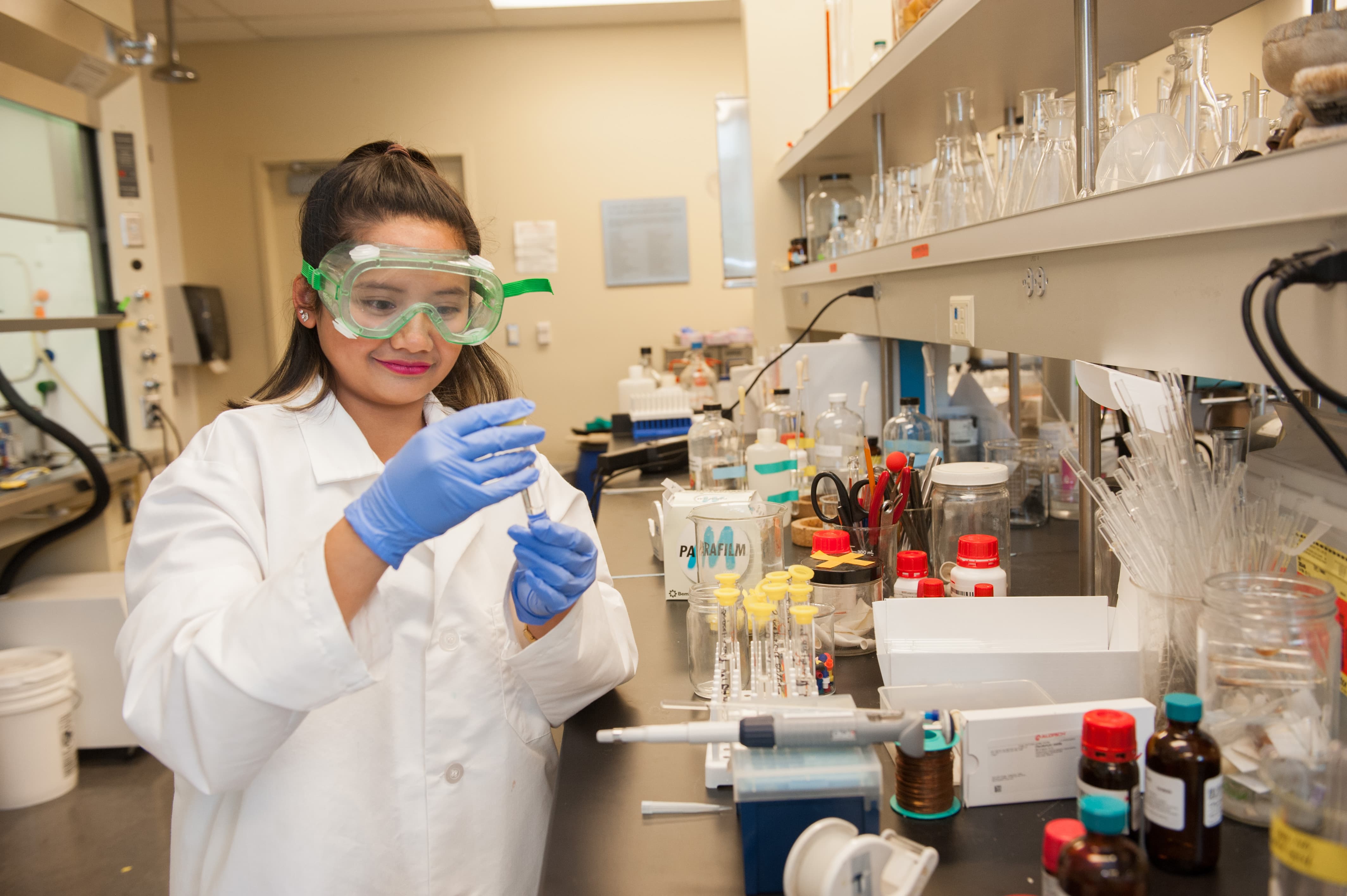 a person wearing protective glasses and holding a test tube