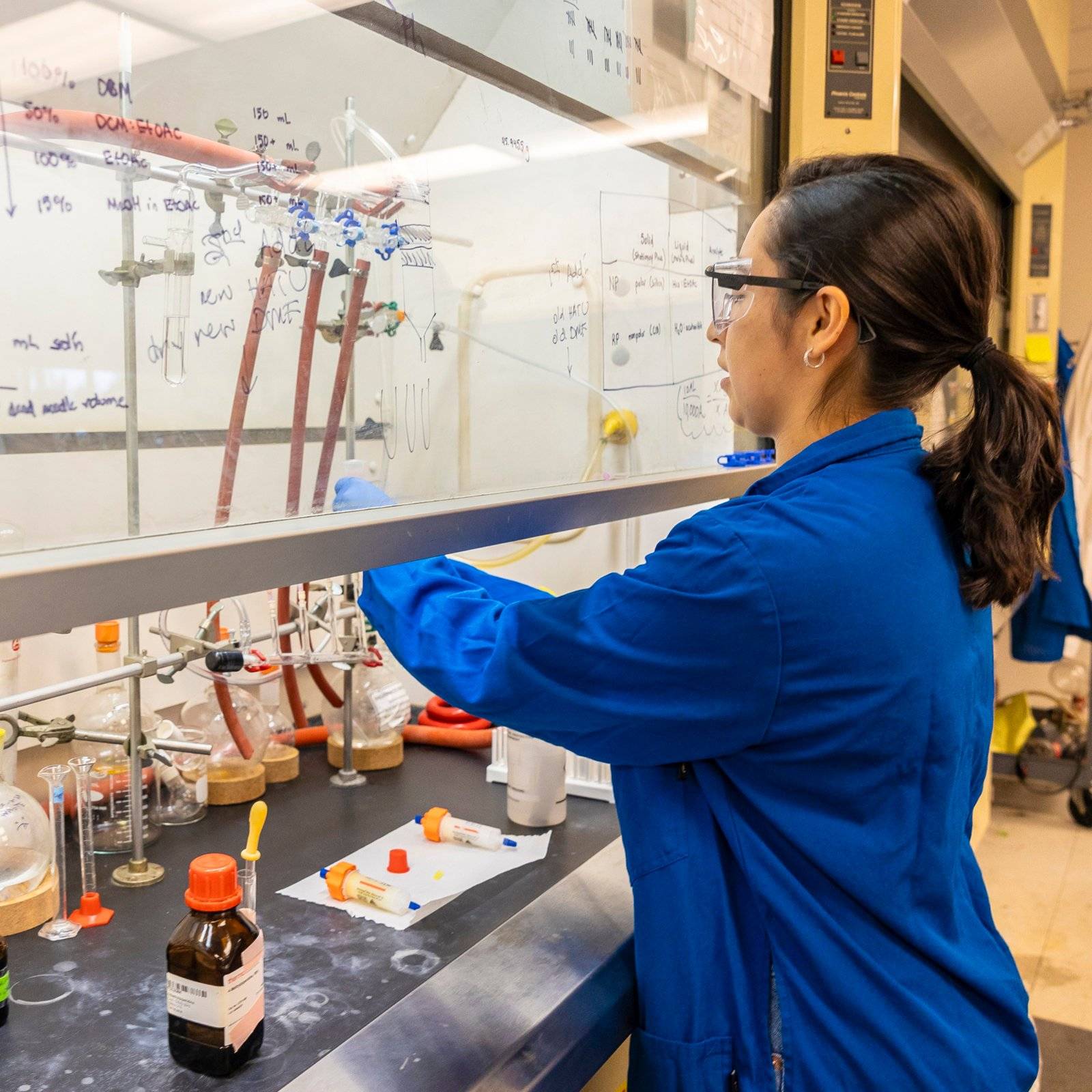 a person in blue lab coat looking at a glass wall