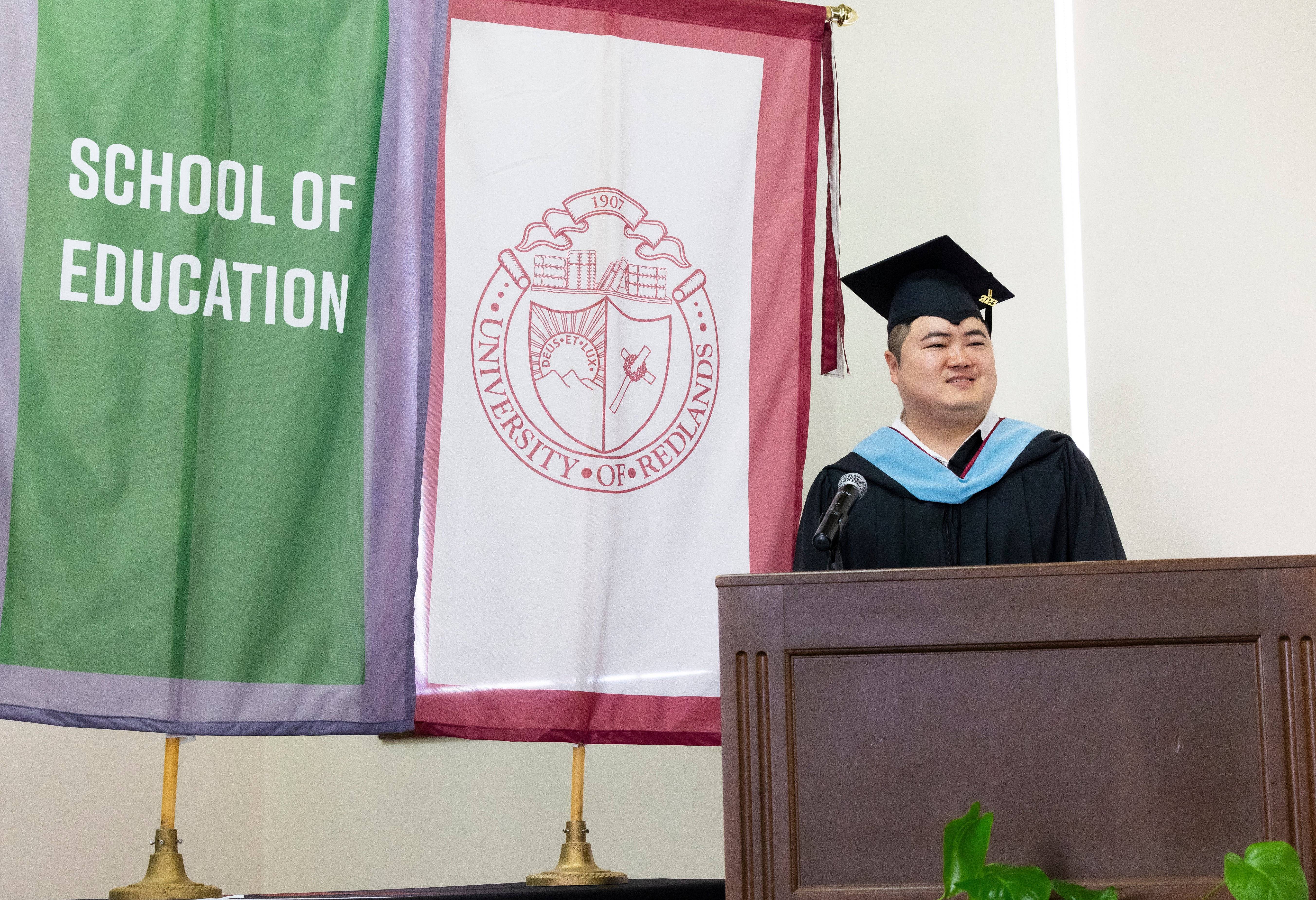 a person in a graduation cap and gown standing at a podium