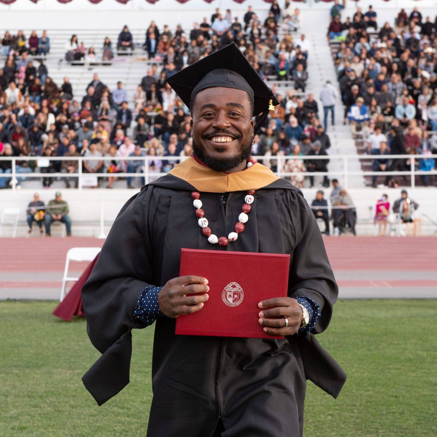 School of Business & Society graduate in a cap and gown holding a diploma during commencement.