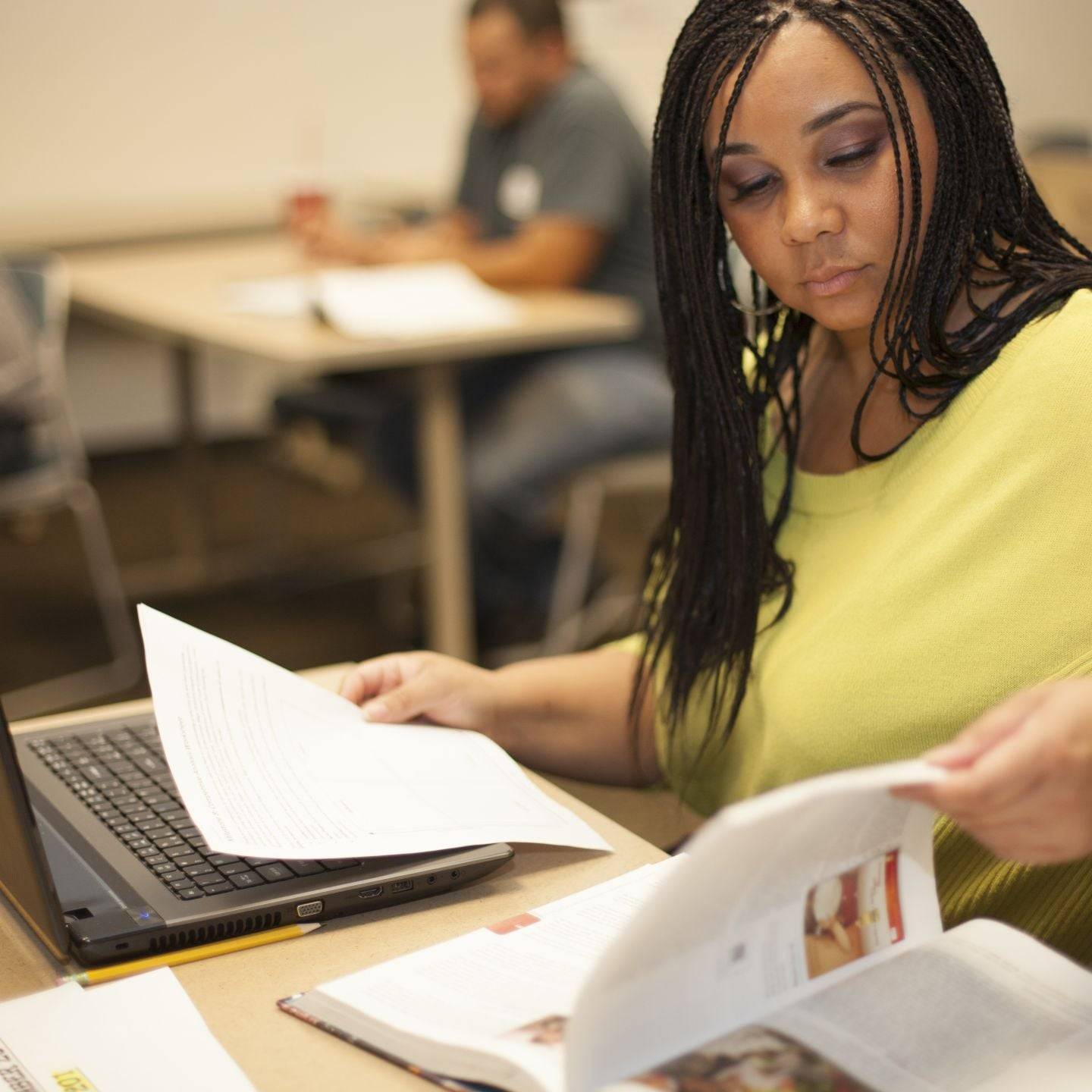 Graduate student reviewing marketing course materials while working on a laptop in class.