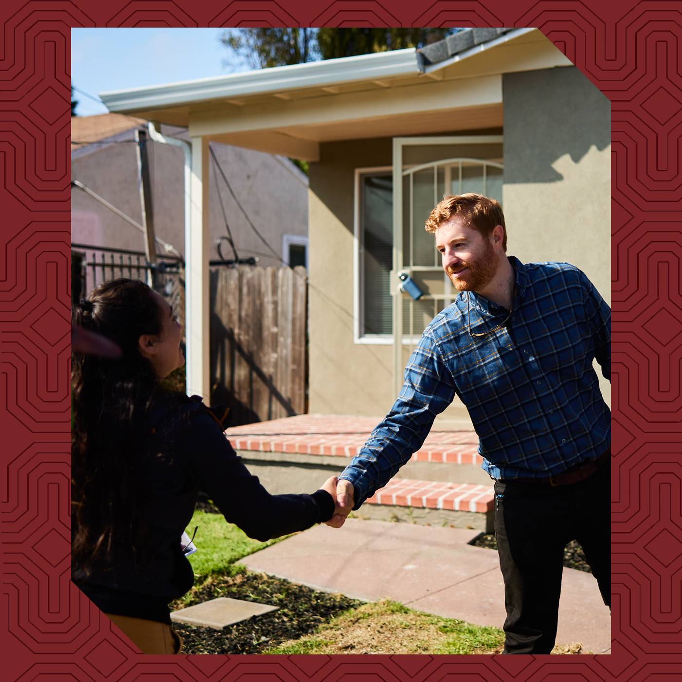 Sam Irvine shakes hands with a community member outside a home.