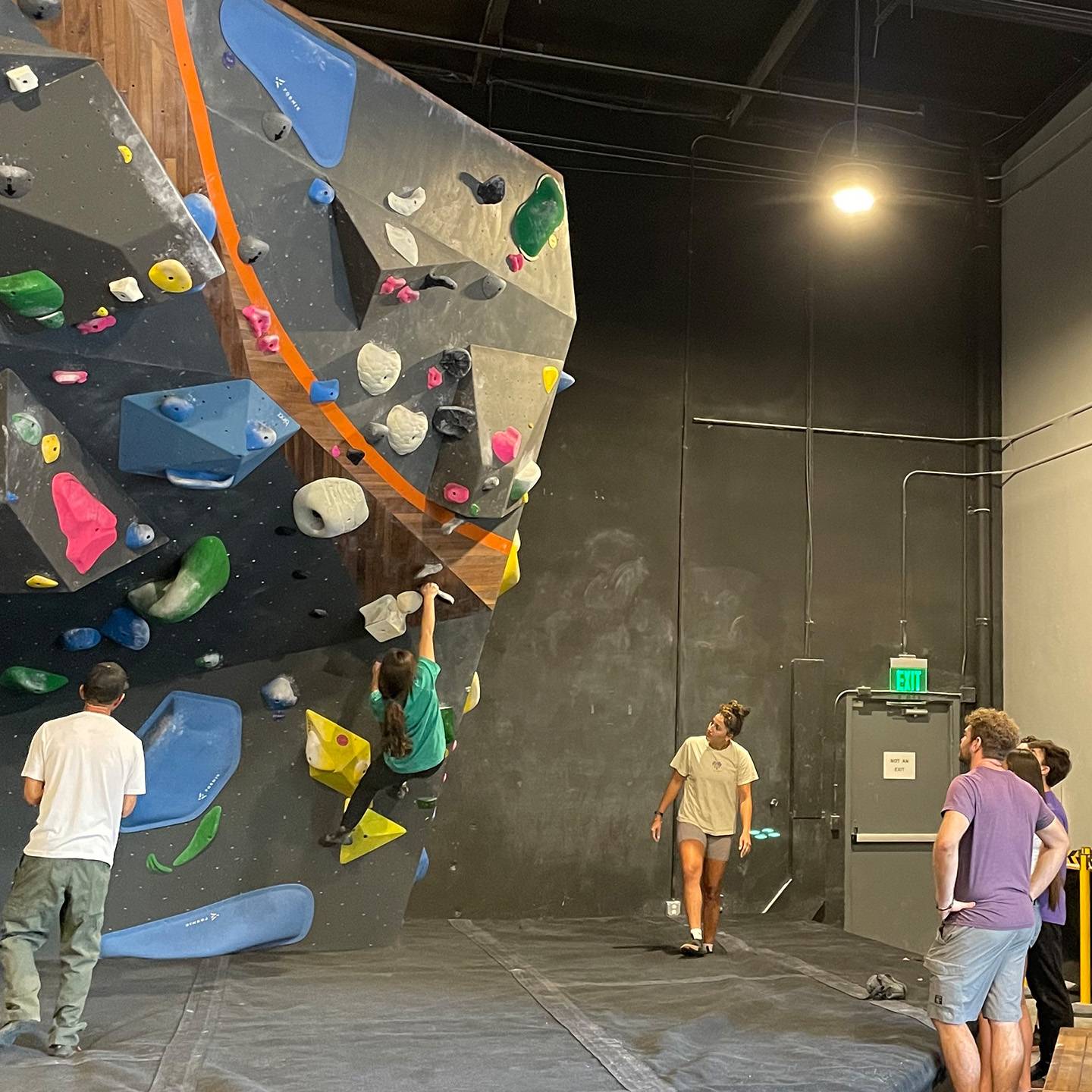 a group of people standing around a rock climbing wall