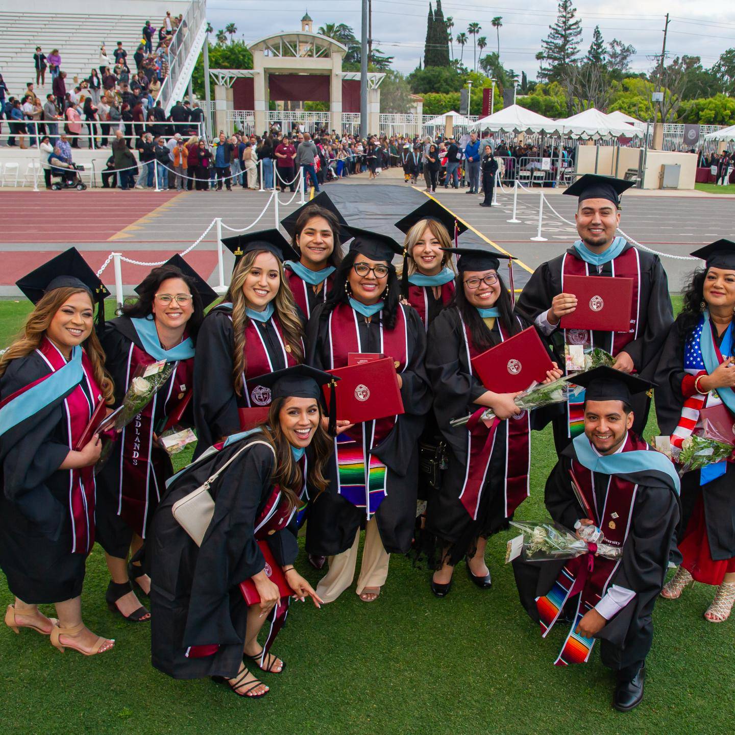 A group photo of graduate students in their cap and gowns holding their diploma.