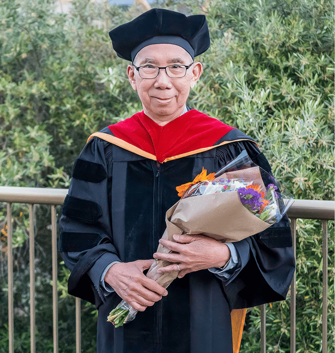 a person in a graduation gown holding flowers