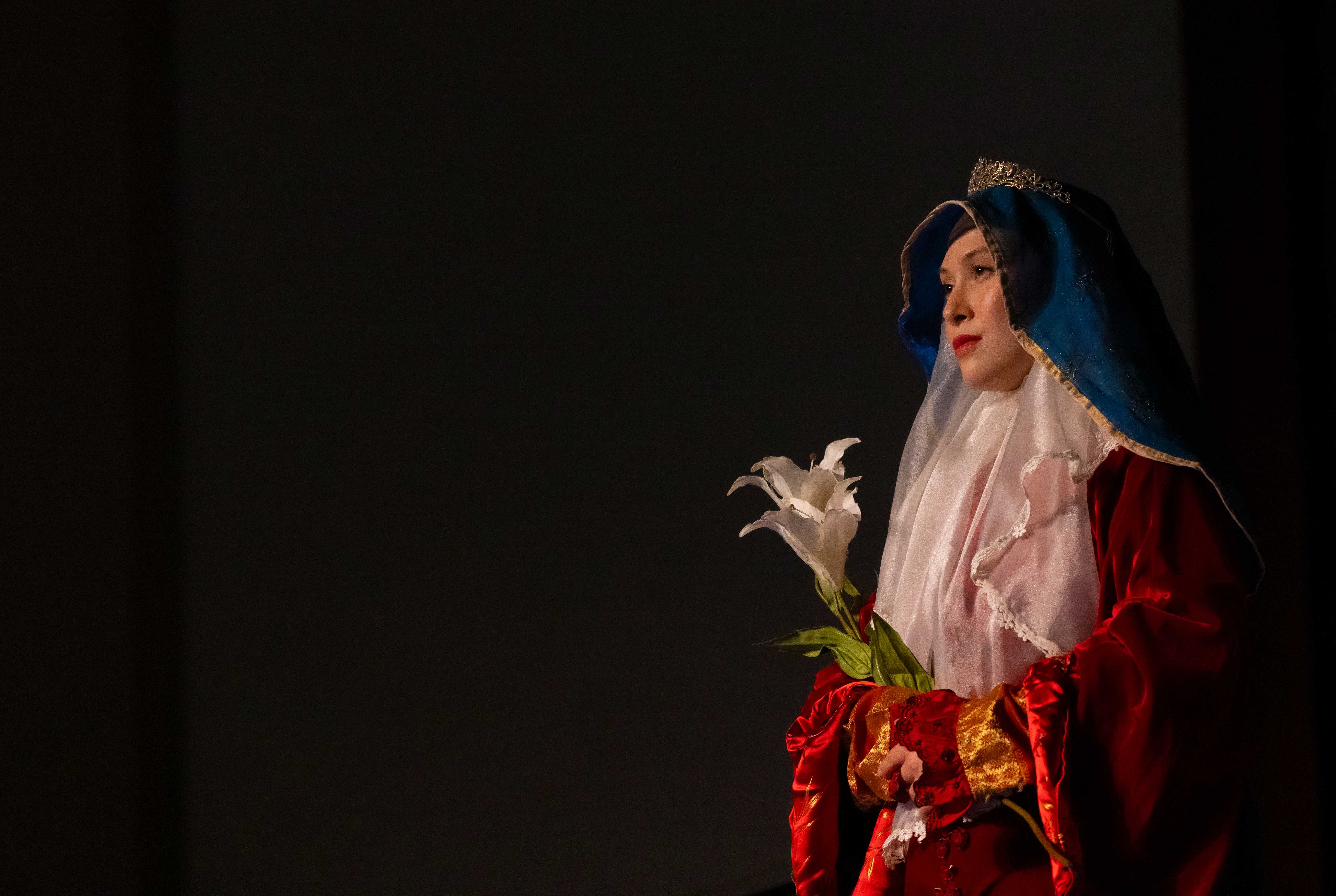 a person in a red robe holding flowers