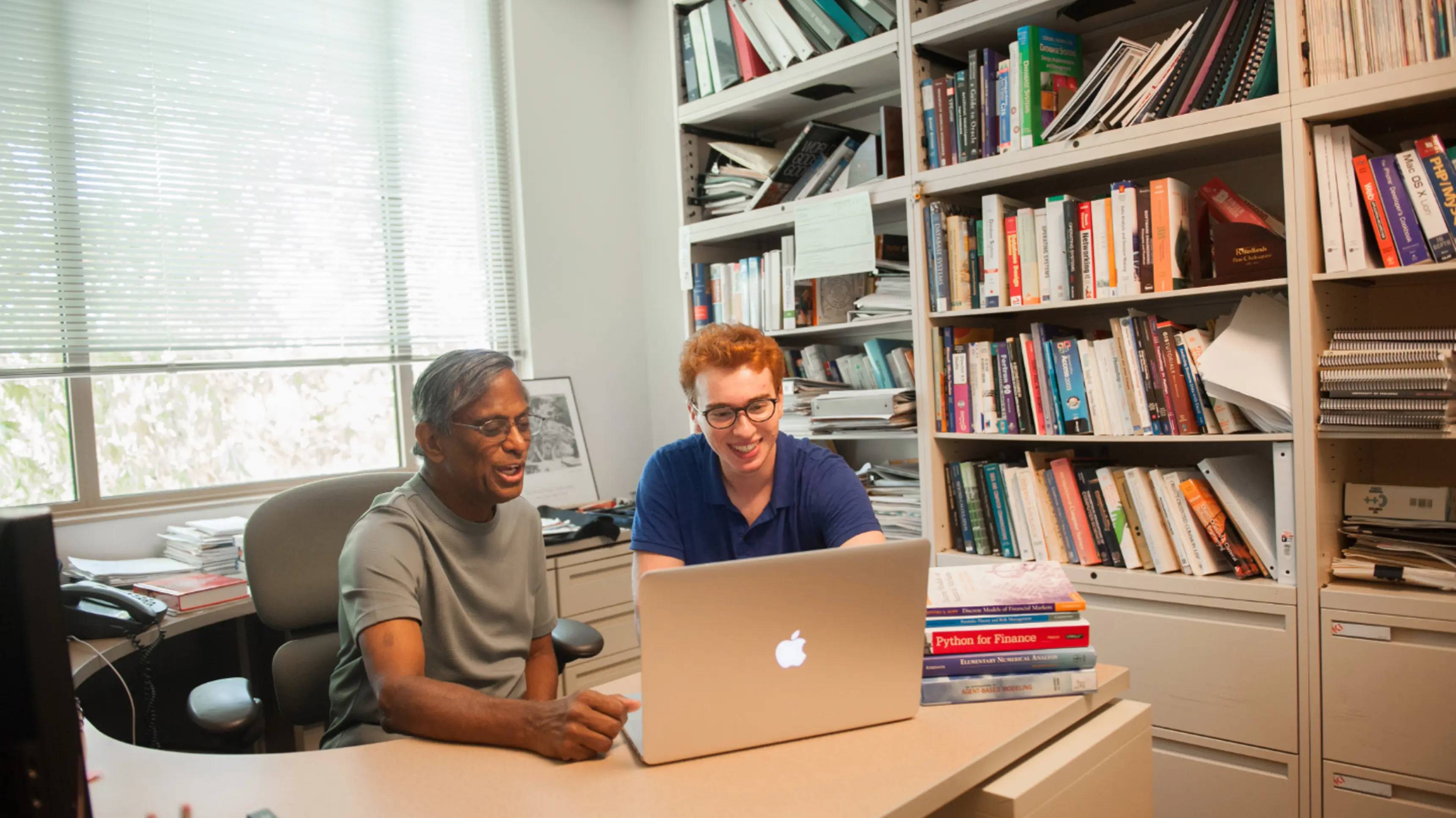 a person and a person looking at a laptop