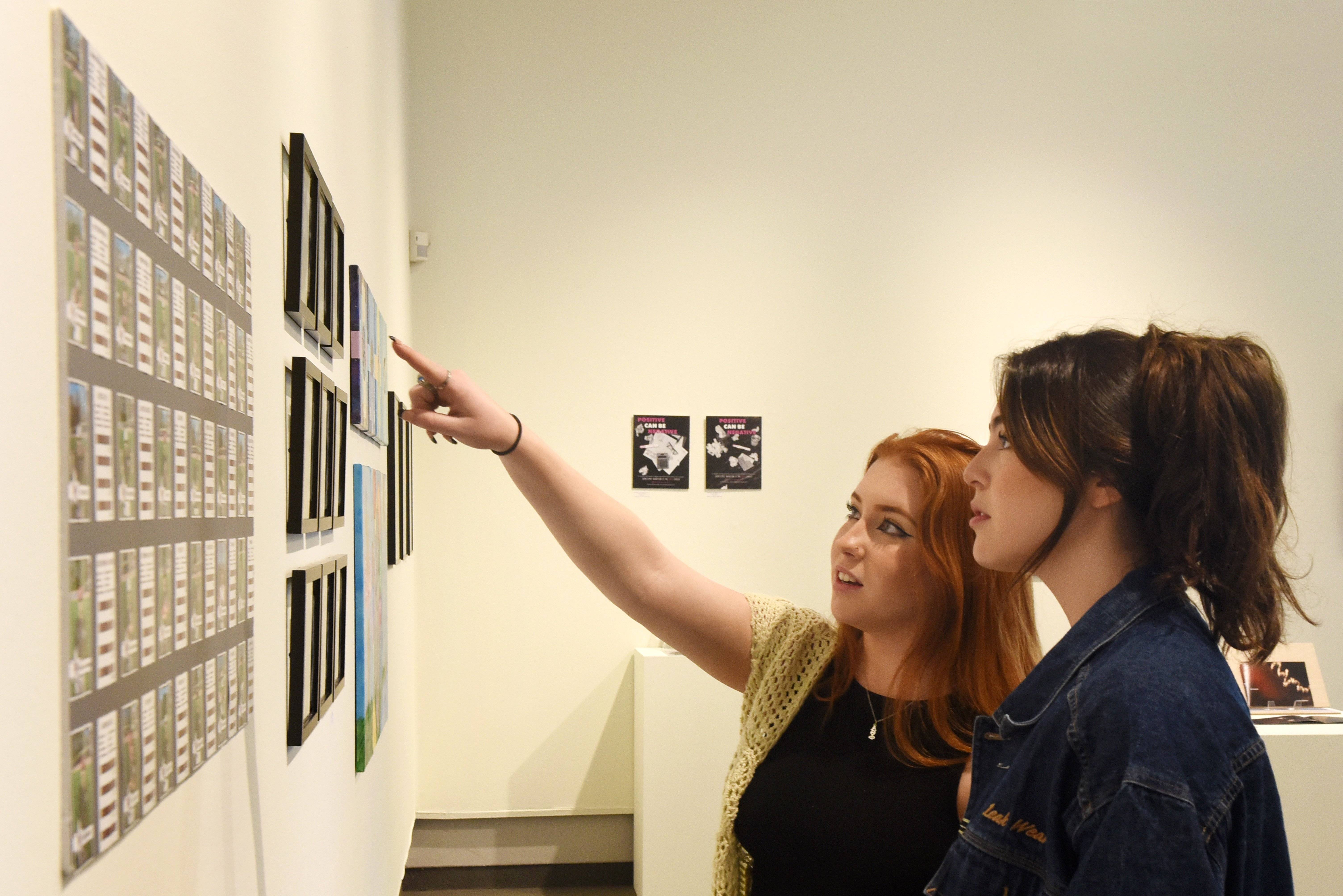a person pointing at a wall with pictures on it