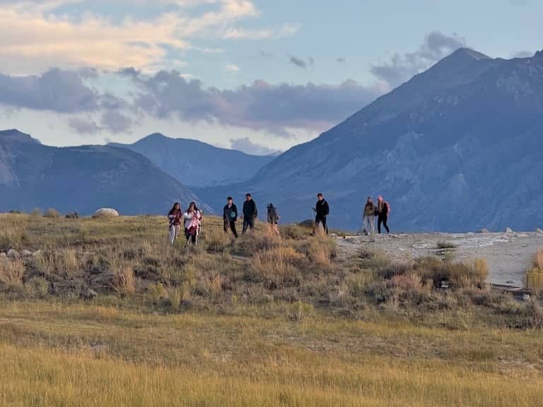 a group of people standing on a hill with mountains in the background