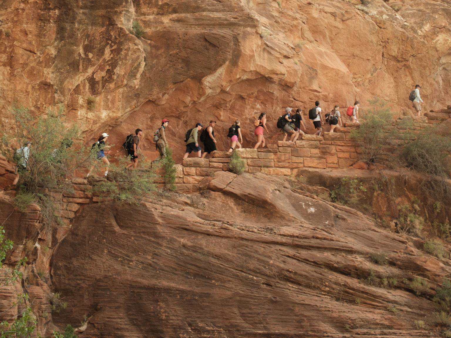 a group of people walking on a rock wall