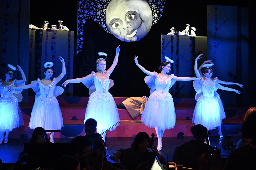 a group of women in white dresses on a stage