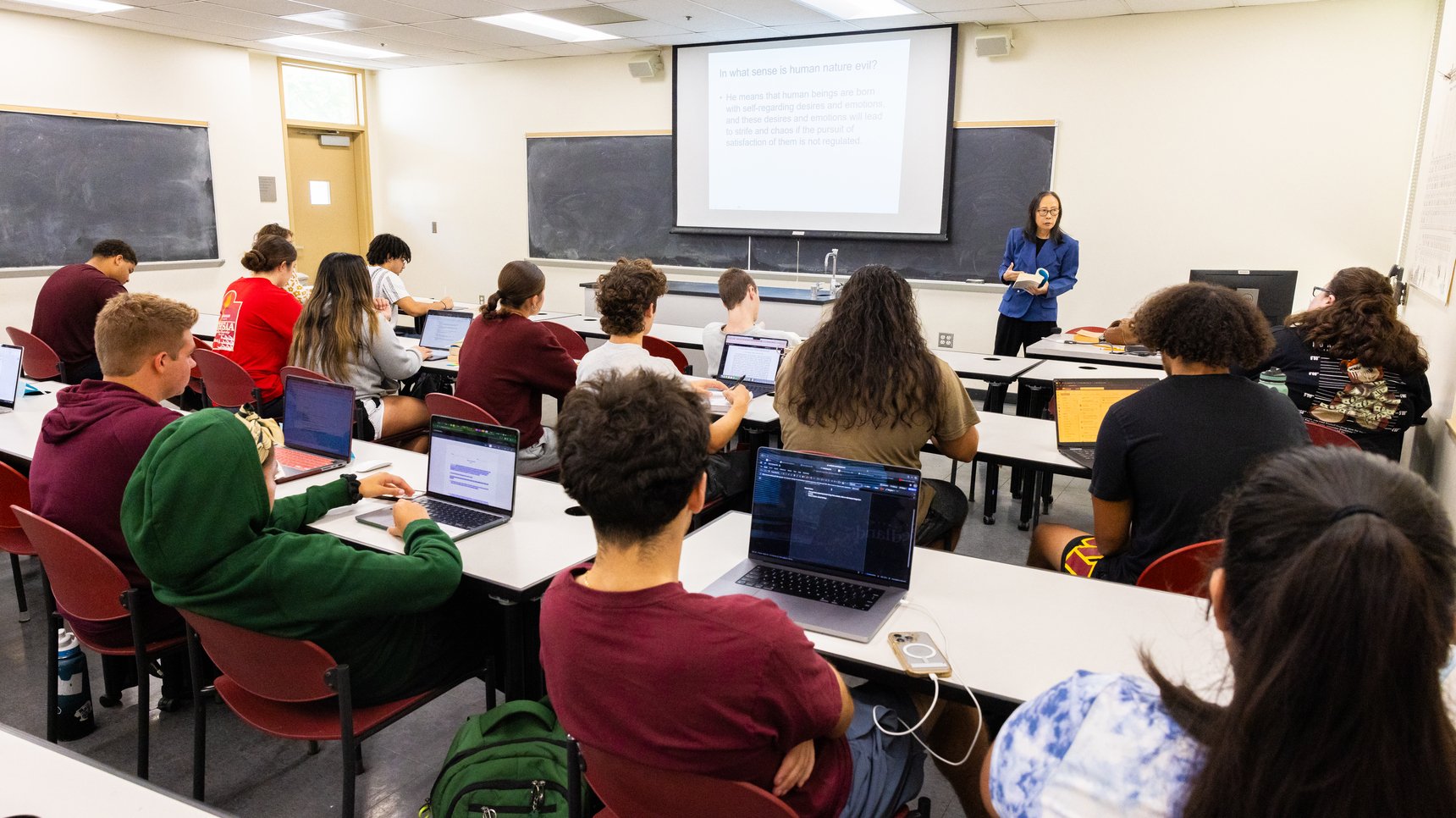 a group of people sitting in a classroom with laptops