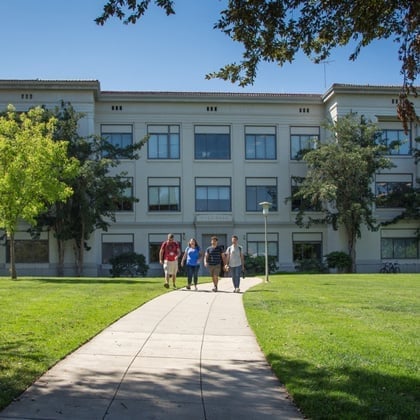 a group of people walking on a sidewalk in front of a building