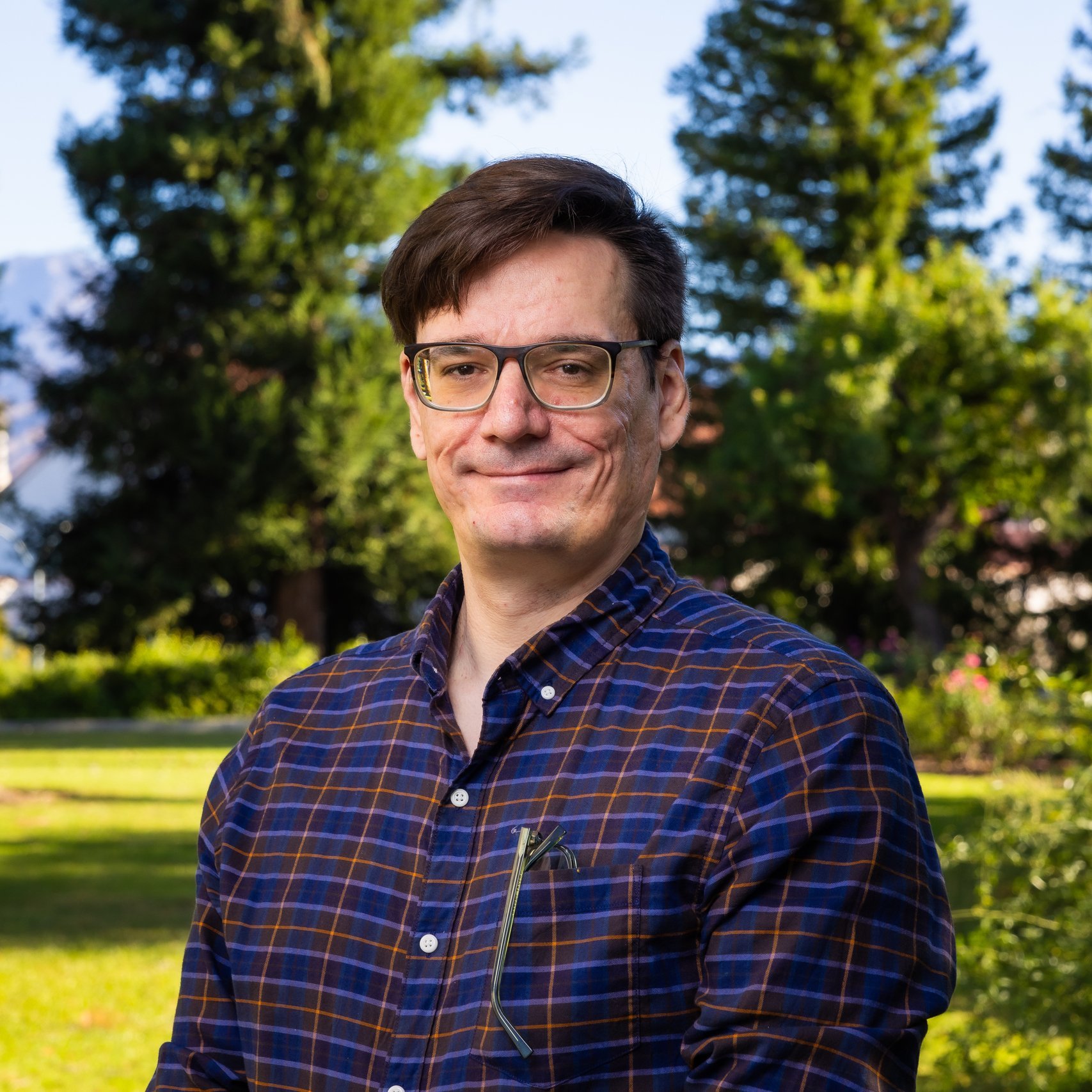 a man wearing glasses and a blue plaid shirt
