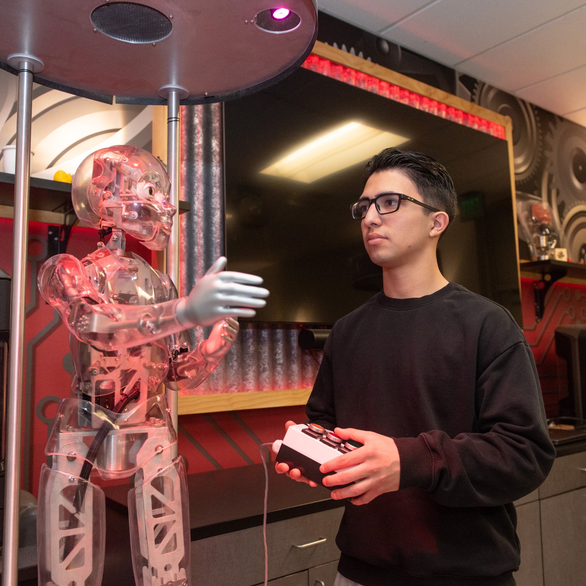 a man holding a controller next to a robot