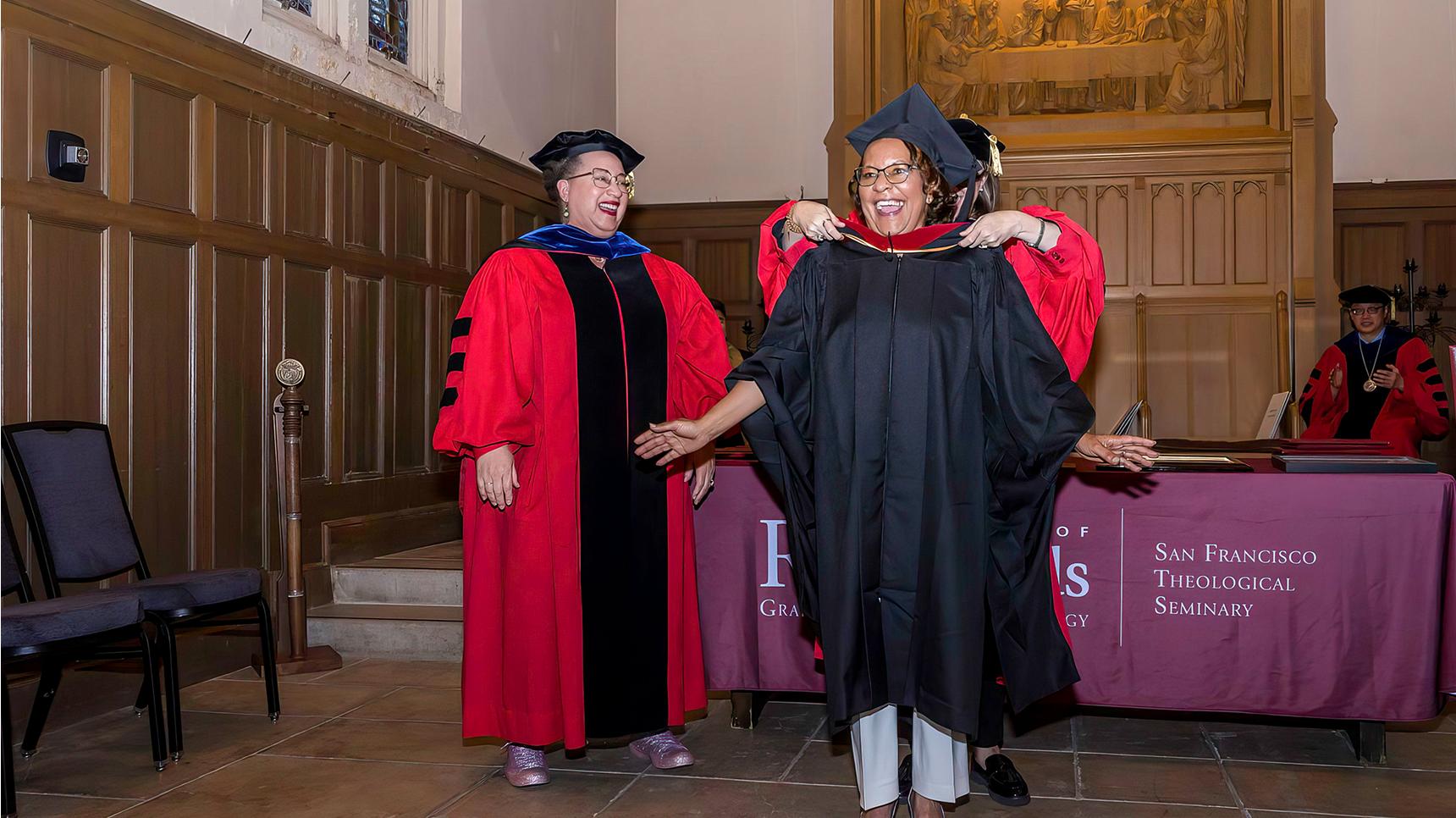 a woman in a graduation gown and cap standing next to a man in a robe