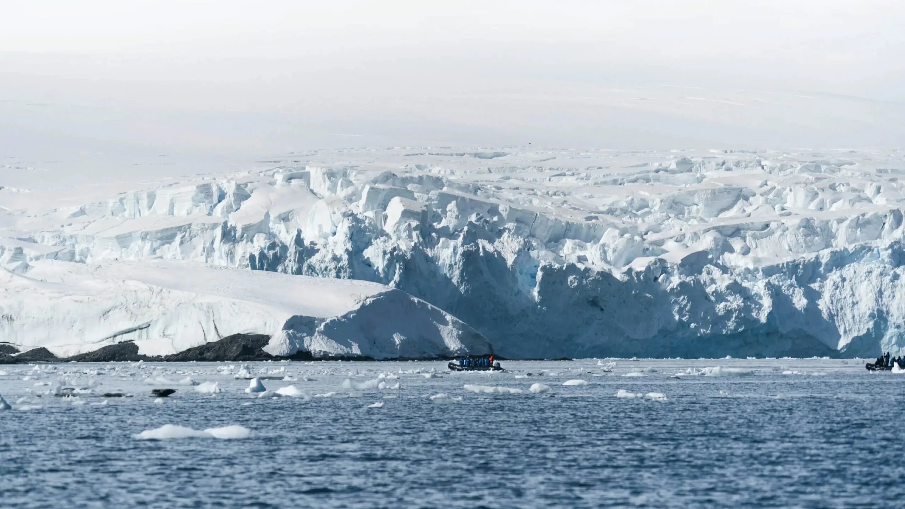 a boat in the water with icebergs in the background