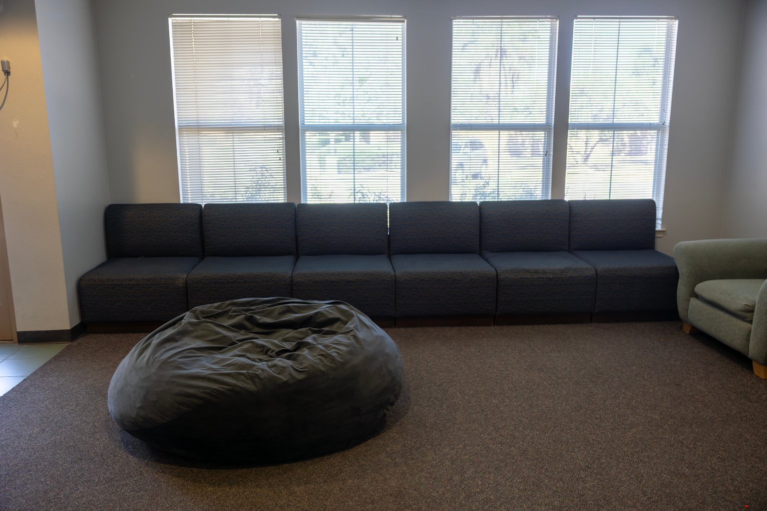 a large bean bag in a room with a long couch and windows