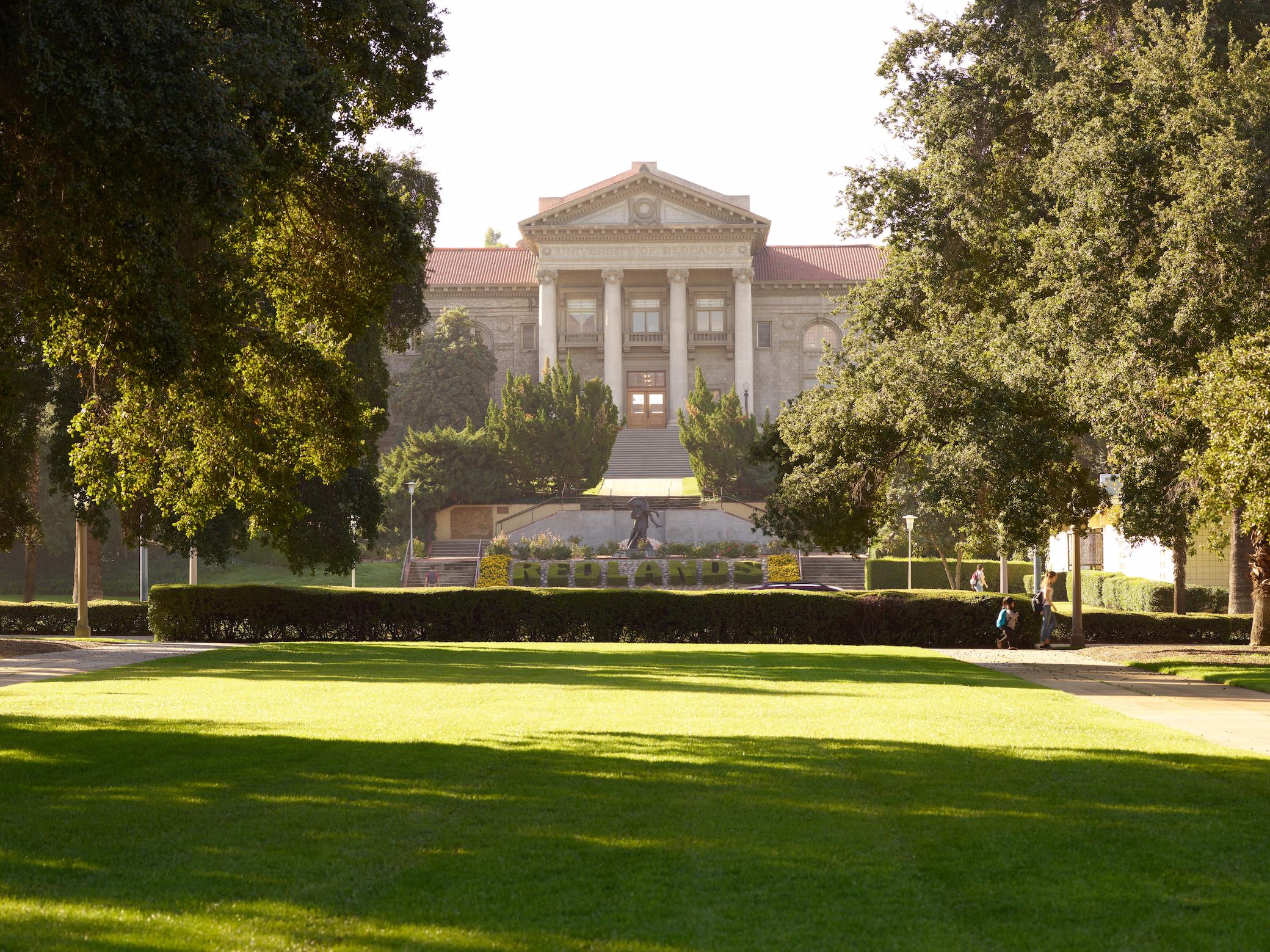 a large building with a lawn and trees