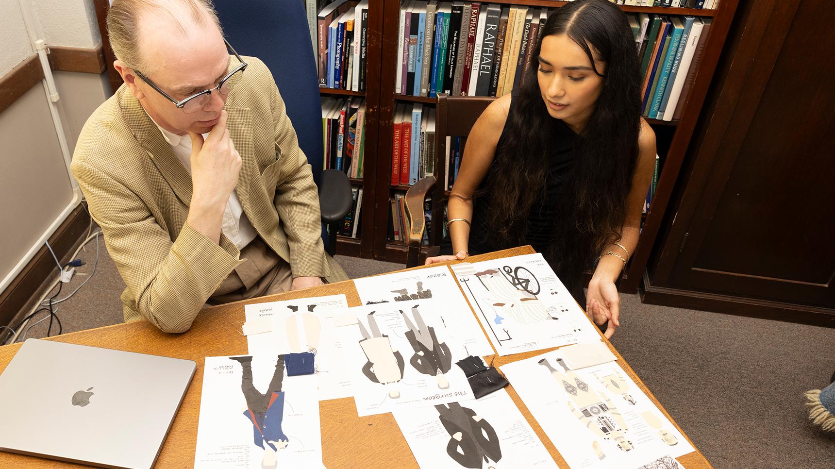 a man and woman looking at a table with paper