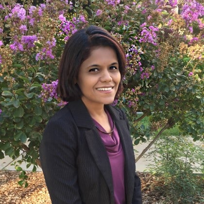 a woman smiling in front of purple flowers