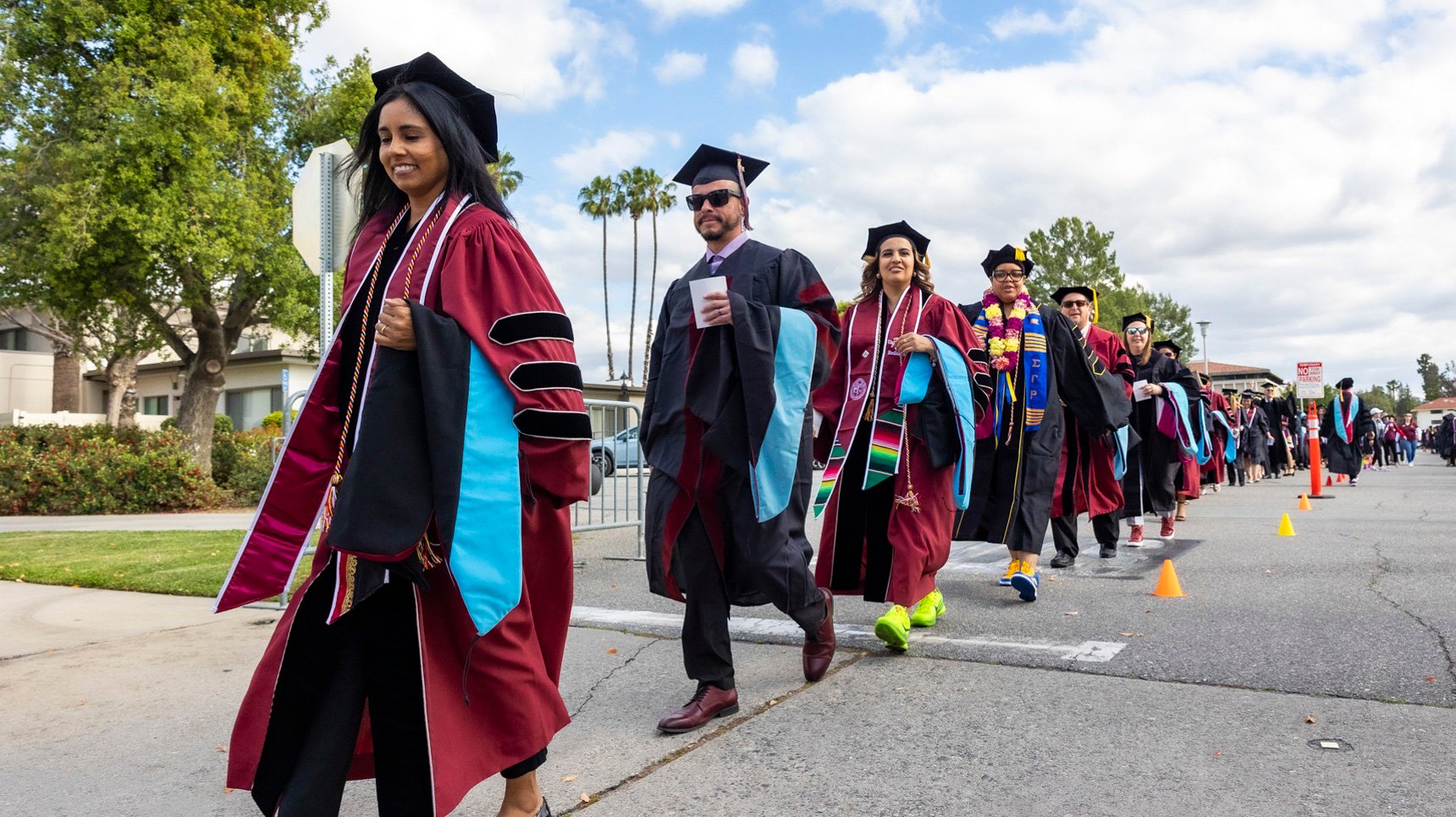 a group of people in graduation gowns walking down a street