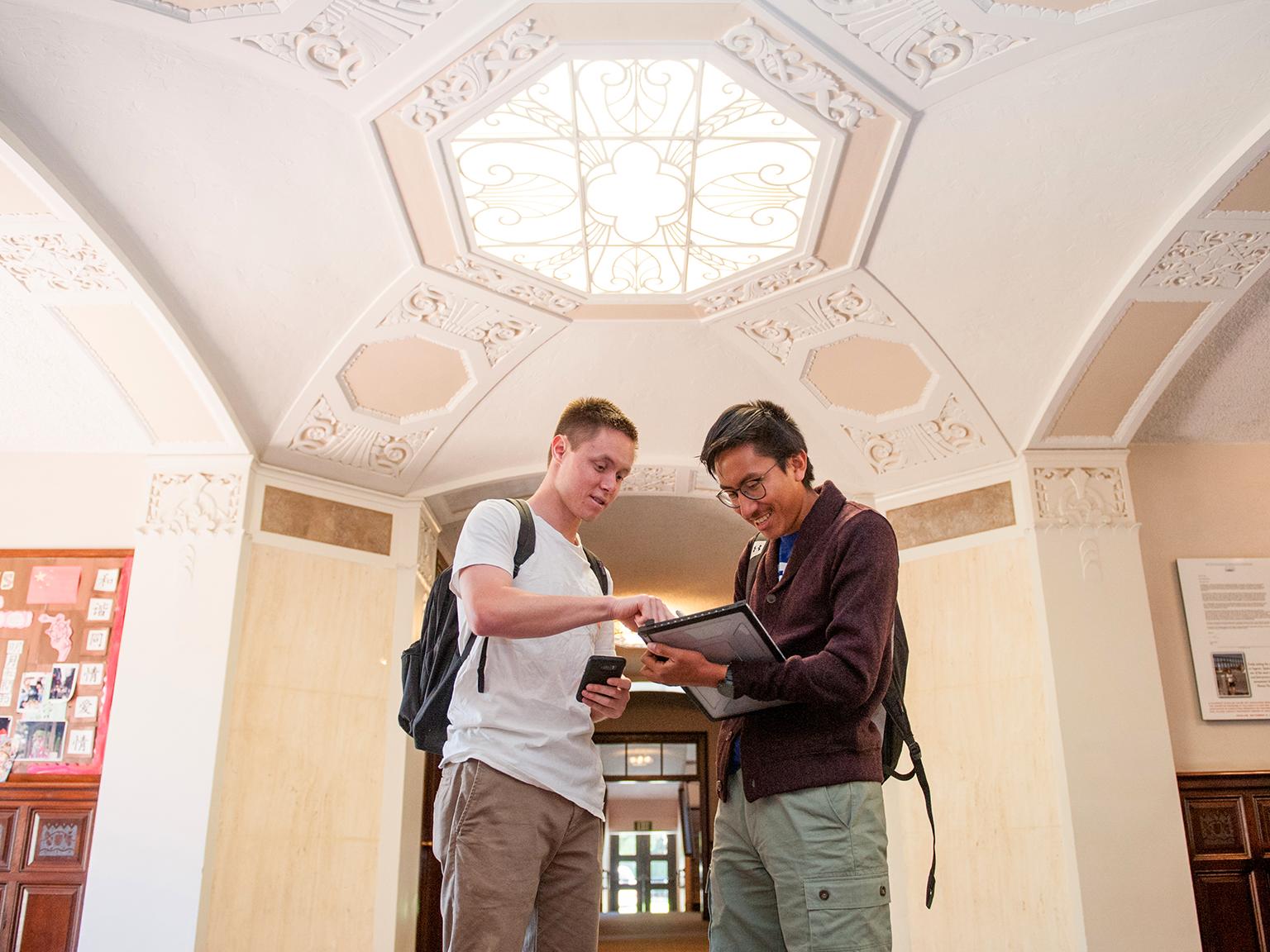 a couple of men looking at a tablet