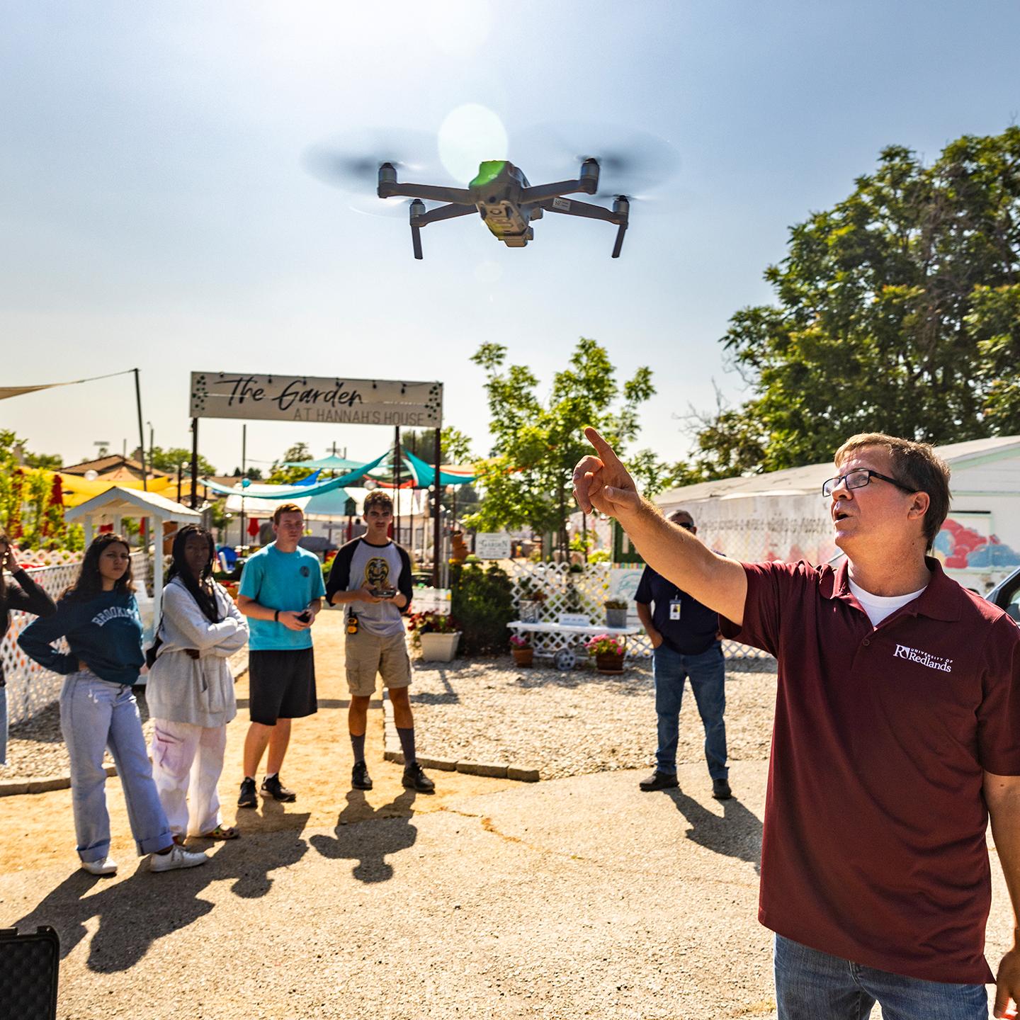A professor pointing at a drone flying in the air