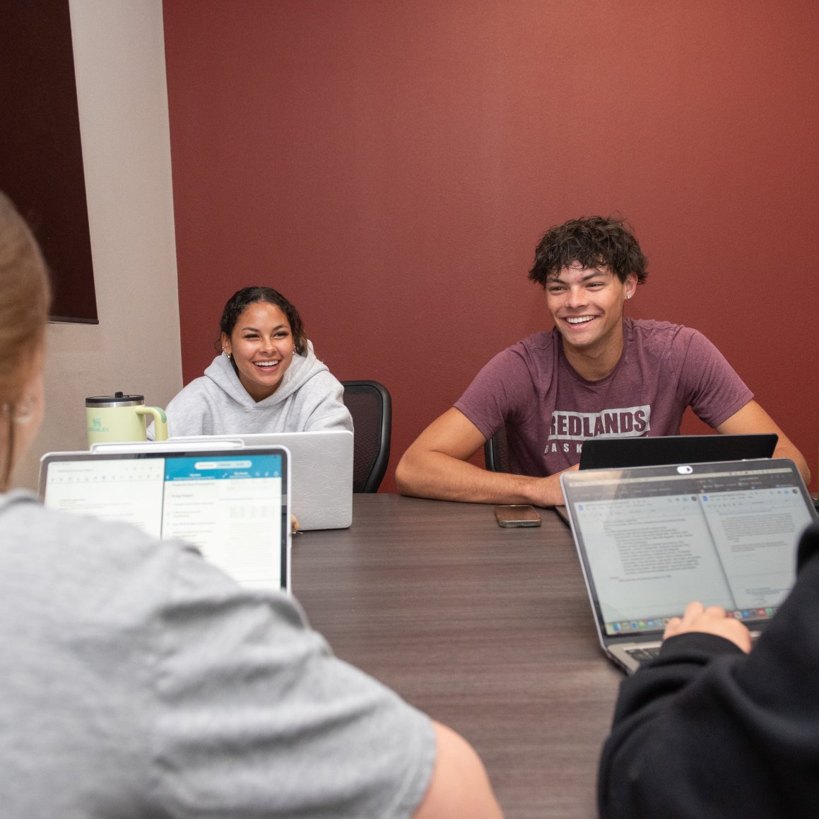 a group of people sitting at a table with laptops