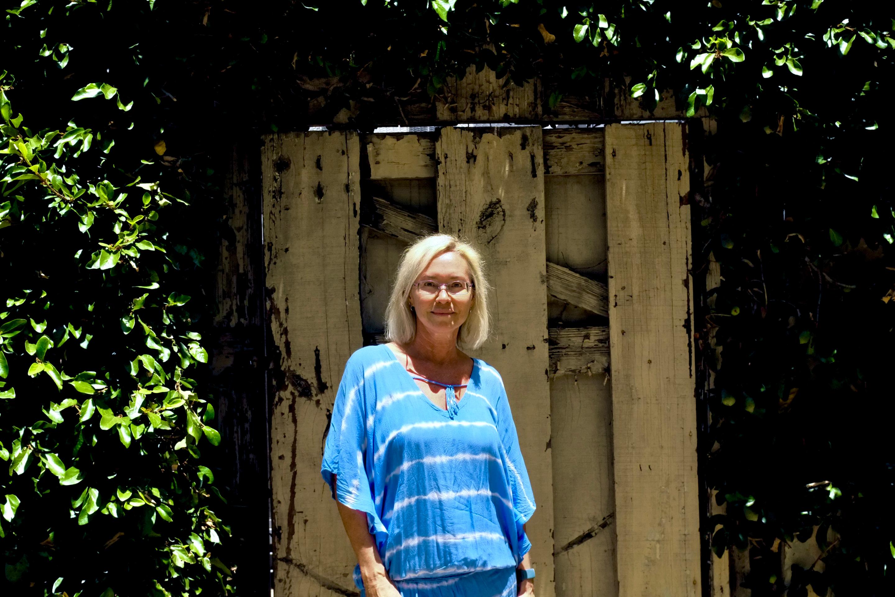 a woman standing in front of a wooden fence