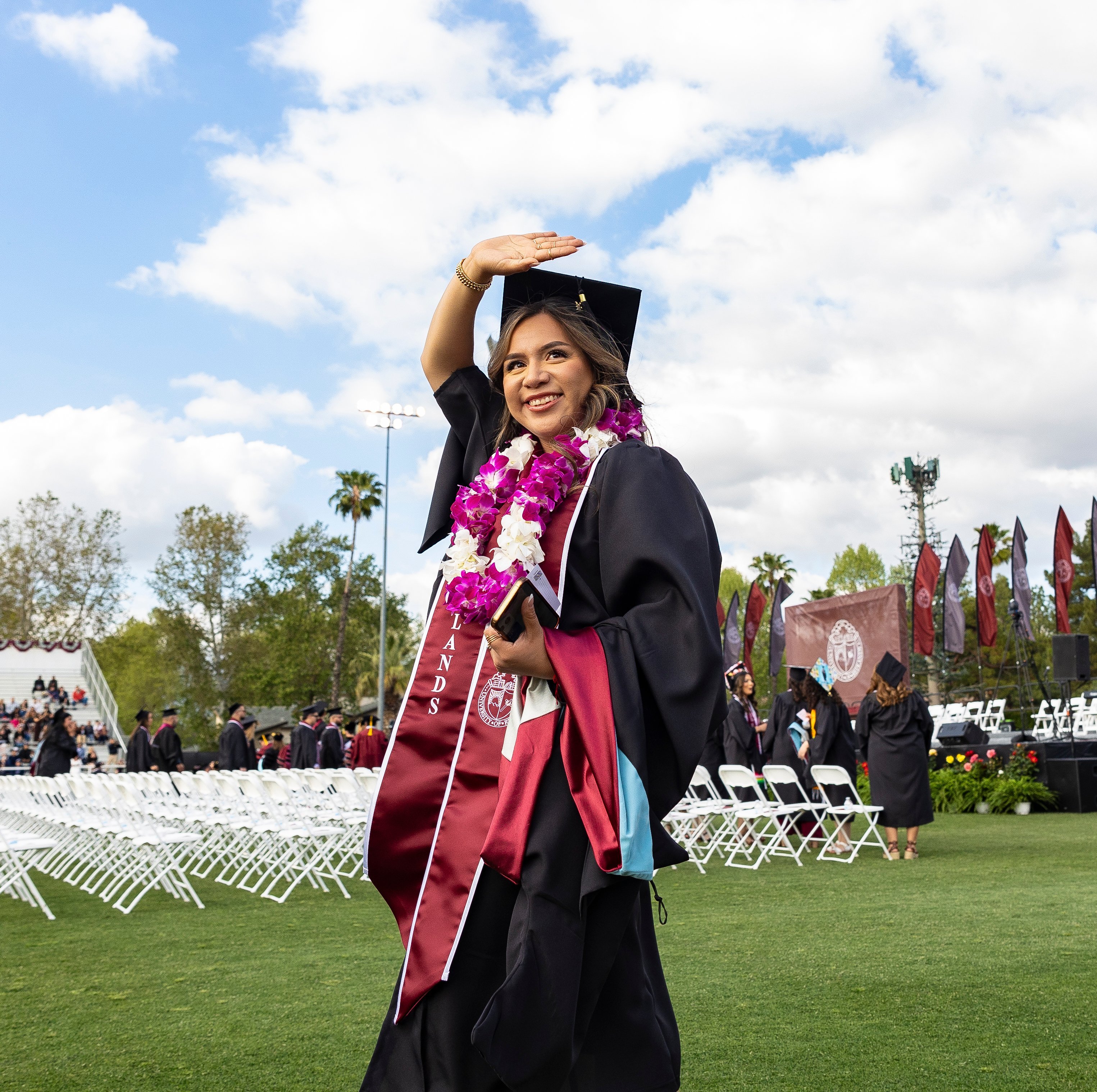 a woman in a graduation gown and cap waving
