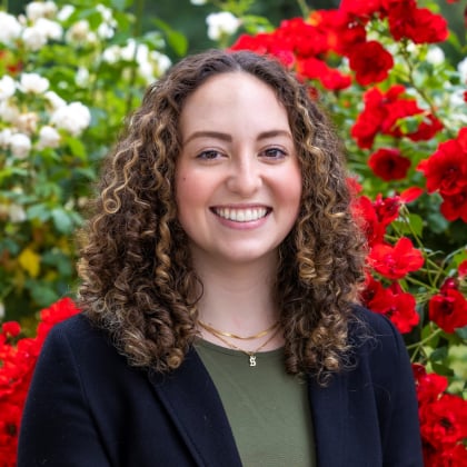 a woman smiling in front of red flowers