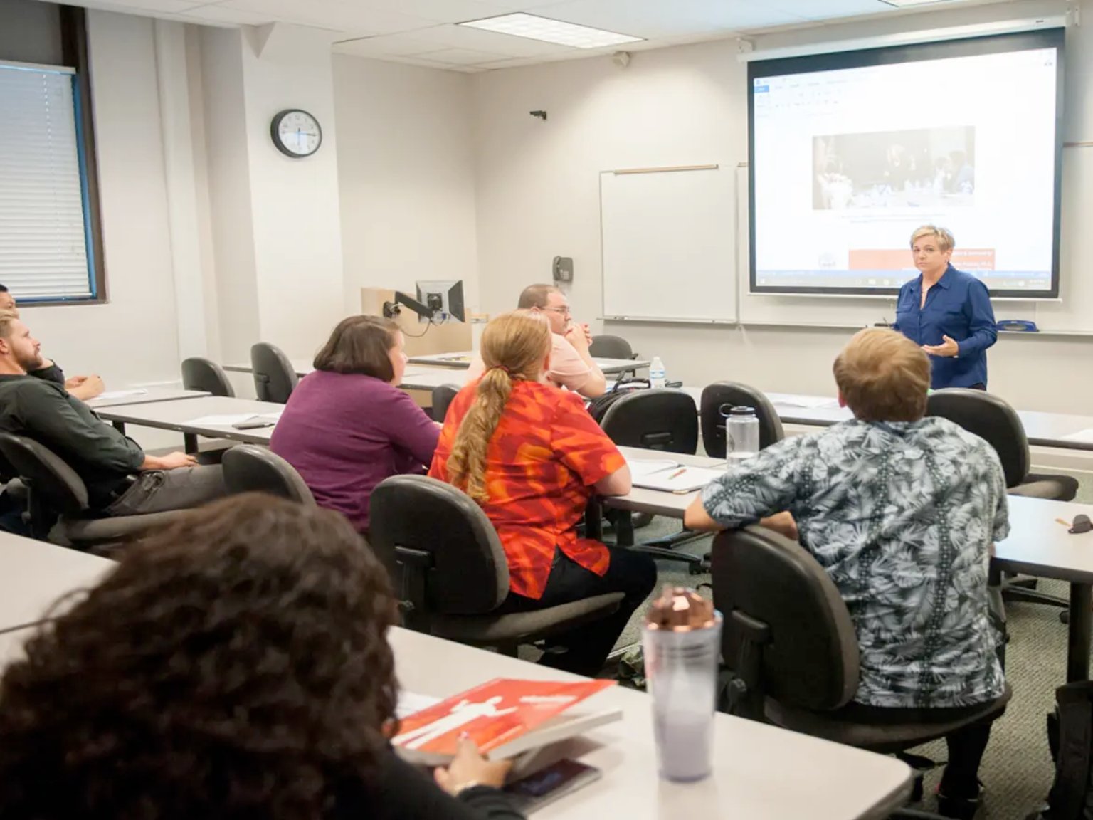 a woman standing in front of a screen in a classroom