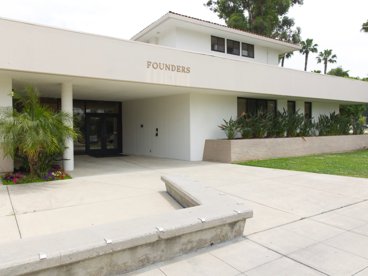 a building with a white wall and a concrete walkway