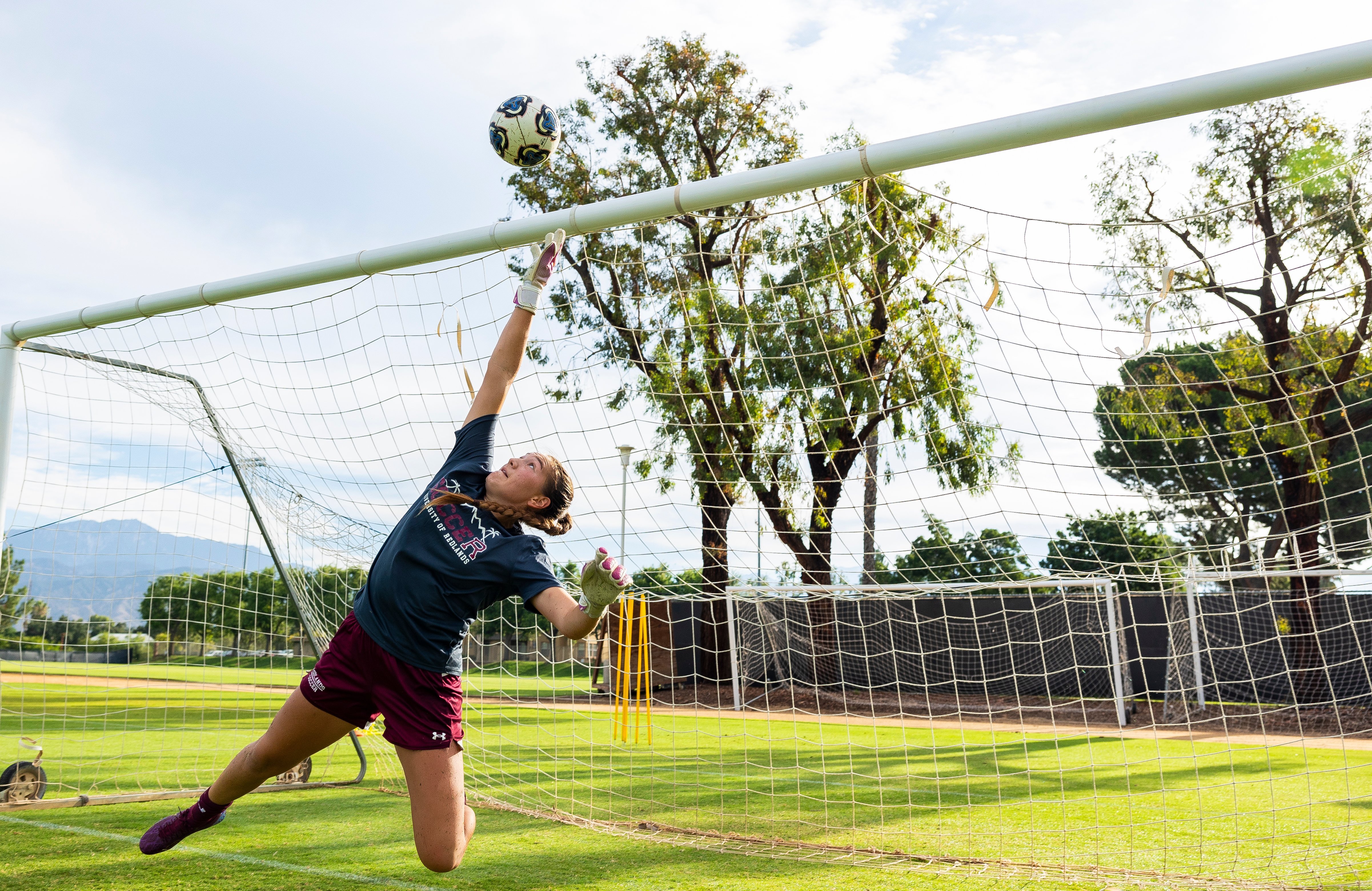 a woman in a football uniform reaching for a football ball