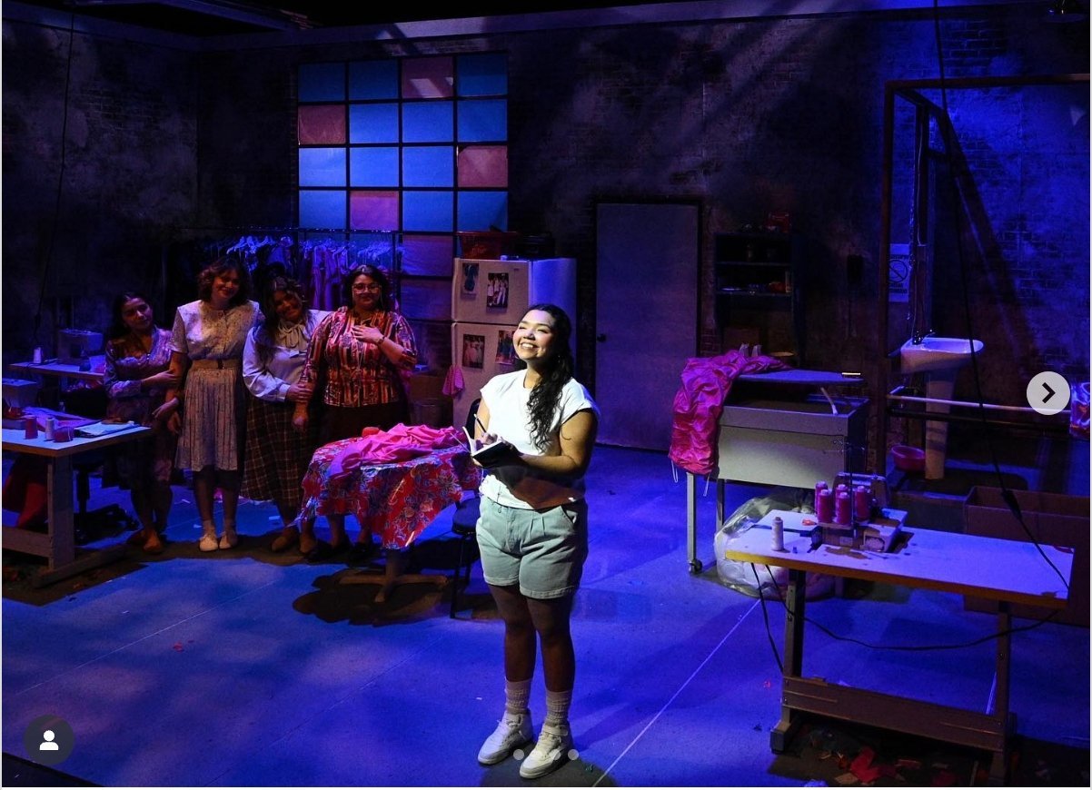 a woman standing in a room with other people behind her